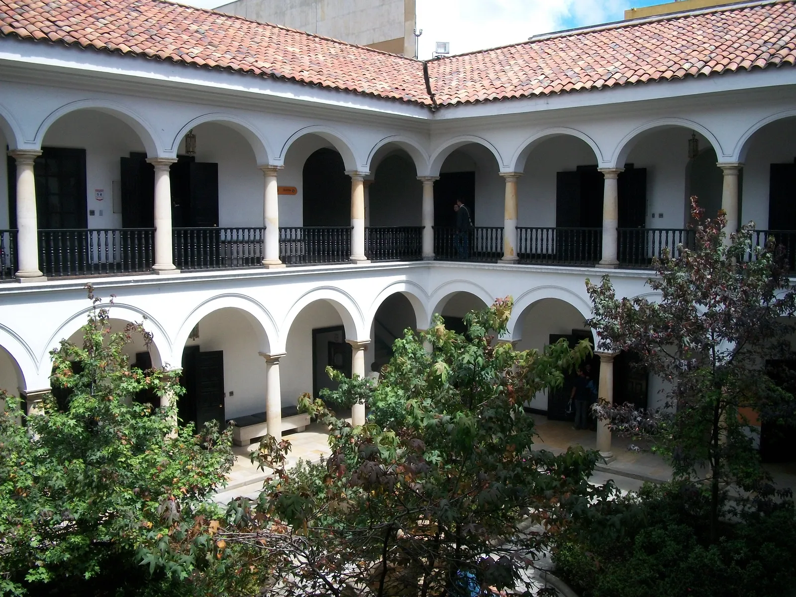The courtyard of the Museo Botero in Bogotá, a white two-storey colonial patio with arcaded galleries on both levels around a planted garden