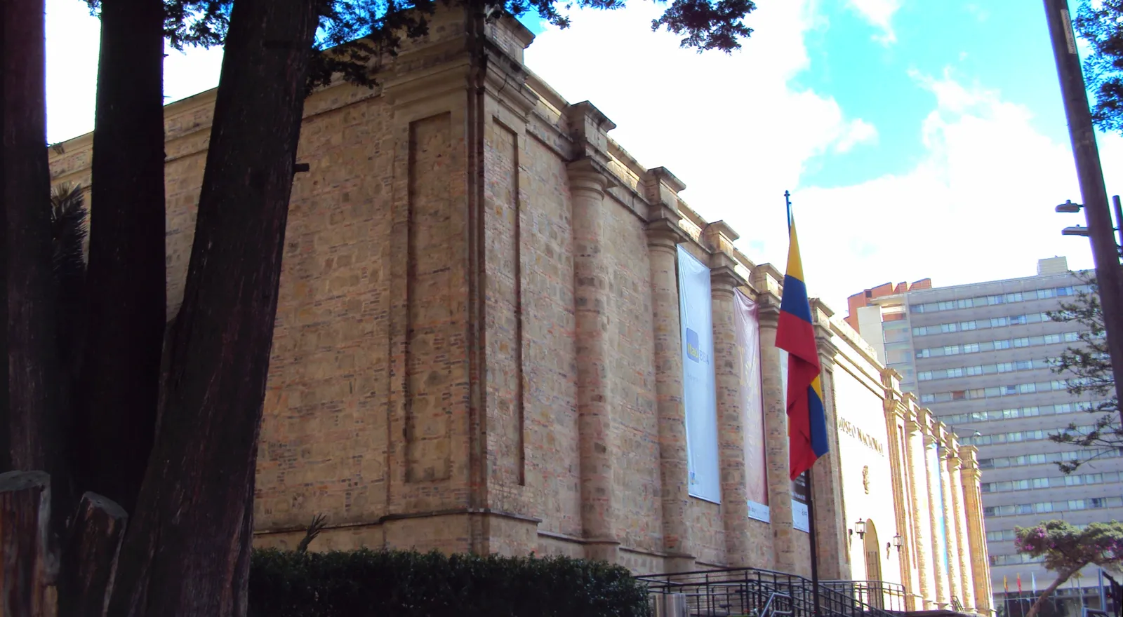 The long stone flank of the Museo Nacional de Colombia in Bogotá, a heavy buttressed nineteenth-century building with a Colombian flag flying beside it