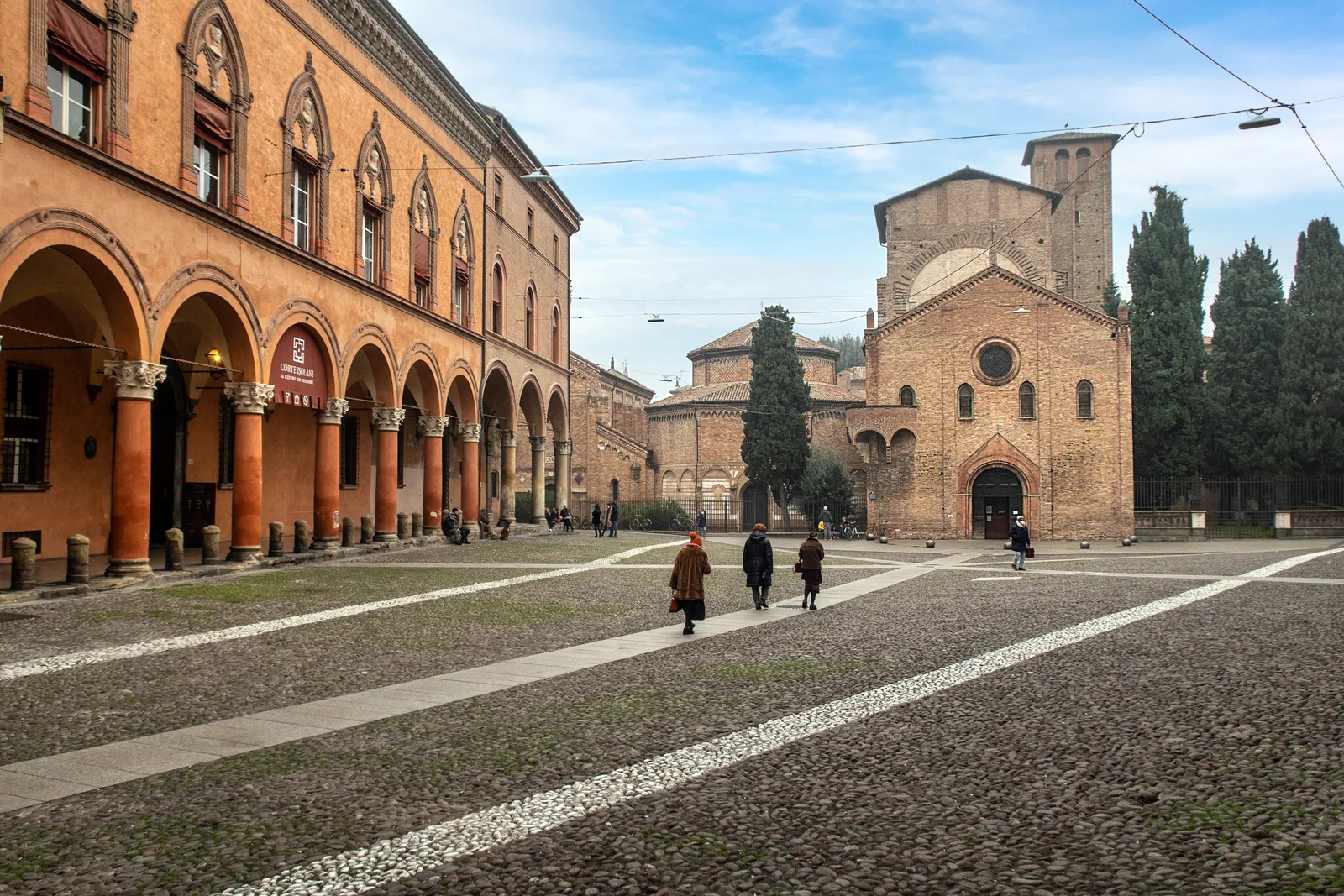 Piazza Santo Stefano in Bologna, a cobbled square with the brick churches of the Santo Stefano complex at one end and arcaded palaces along its side