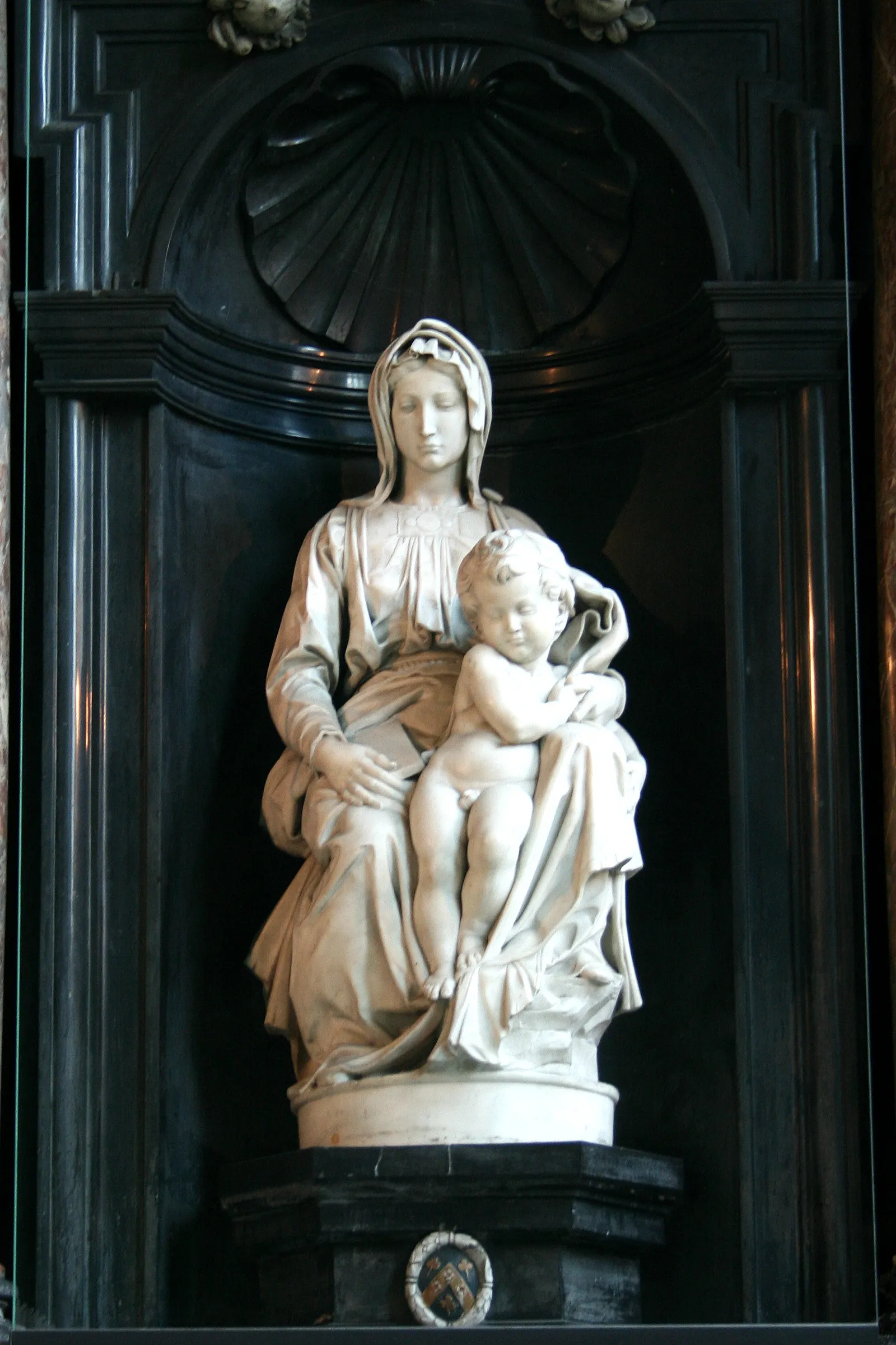 Michelangelo's marble Madonna and Child in the Church of Our Lady in Bruges, the seated Virgin and the standing infant Christ set in a black stone niche