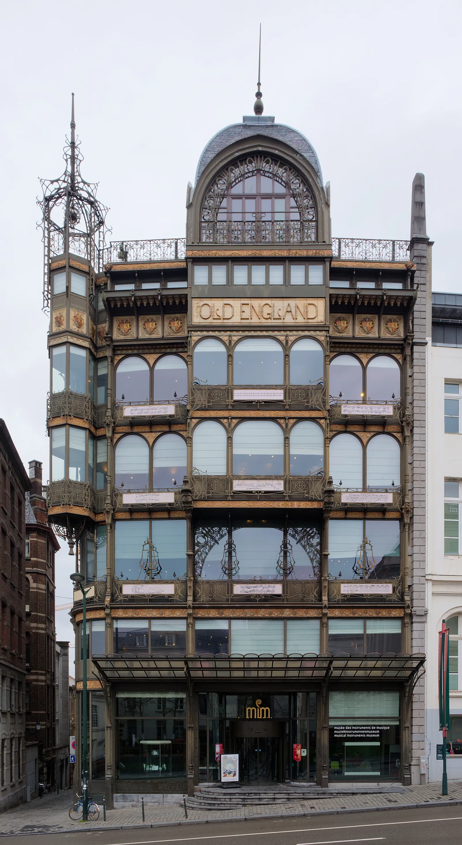 The Old England building in Brussels, a shopfront of black ironwork and glass with the store's name in gold lettering across the facade and a domed corner turret above