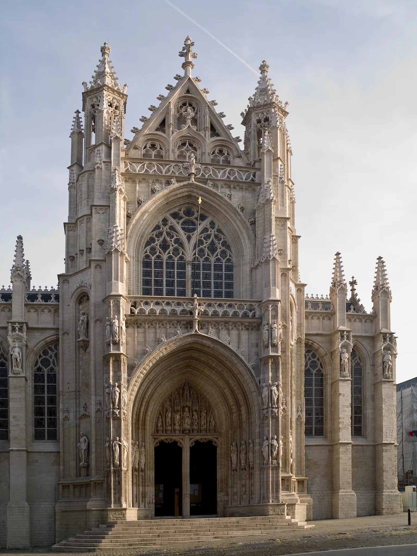 The stone west front of Notre-Dame du Sablon in Brussels, a late Gothic church with a deep arched porch, pinnacled buttresses and a tall traceried window above the doors