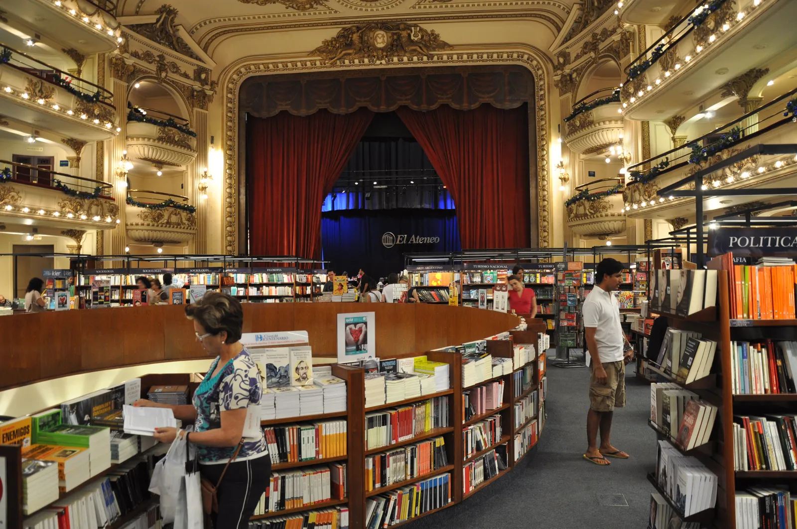 The interior of El Ateneo Grand Splendid bookshop in Buenos Aires, with bookshelves filling the stalls of a former theatre, tiers of ornate balconies along the walls and a red stage curtain at the far end