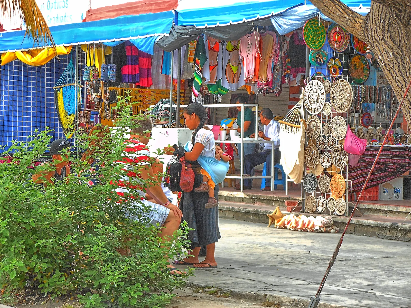 Craft stalls at Mercado 28 in downtown Cancún, striped hammocks and embroidered cotton hanging across the openings beside racks of woven discs and painted goods
