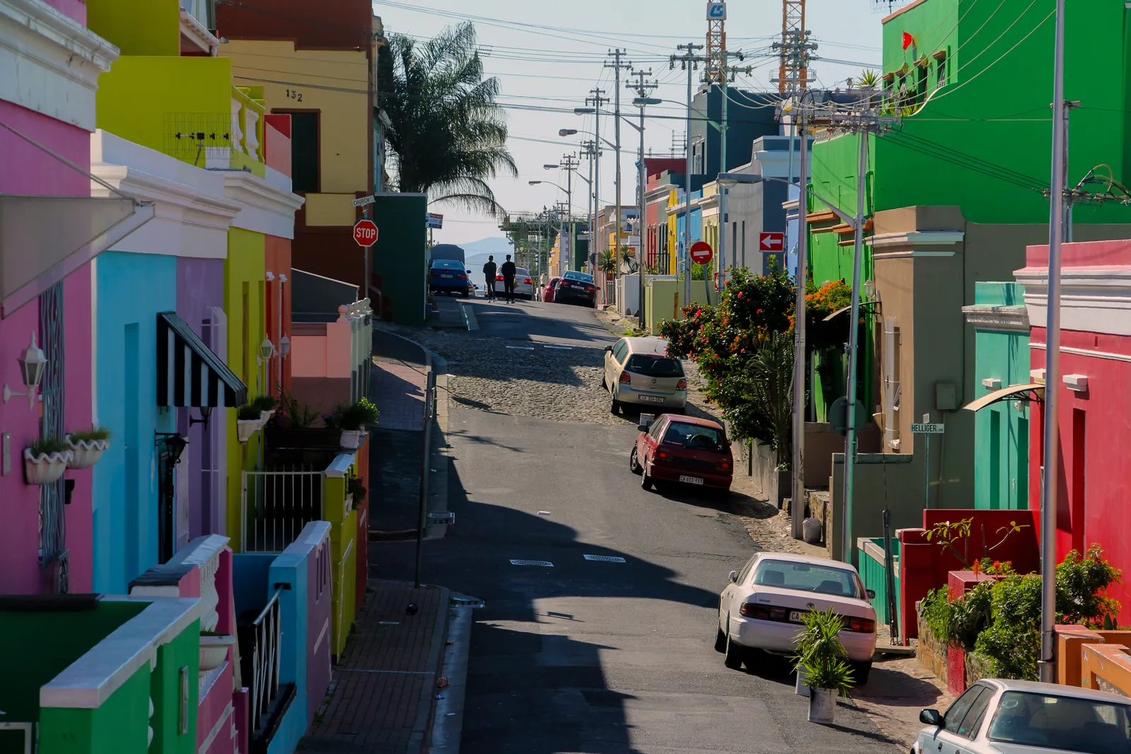 Chiappini Street in Cape Town's Bo-Kaap, a narrow sloping street lined with flat-roofed houses painted pink, lime green, sky blue and yellow, with a stretch of cobbles in the roadway