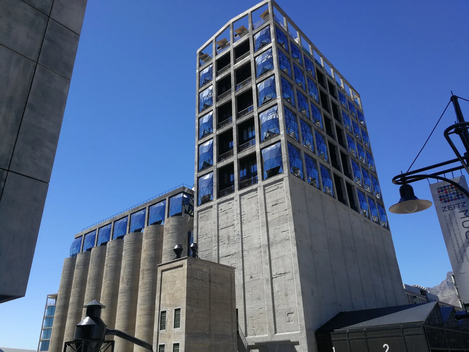 Zeitz MOCAA at Cape Town's V&A Waterfront, a tall concrete grain silo tower and the row of silo tubes beside it topped with bulging, faceted glass windows