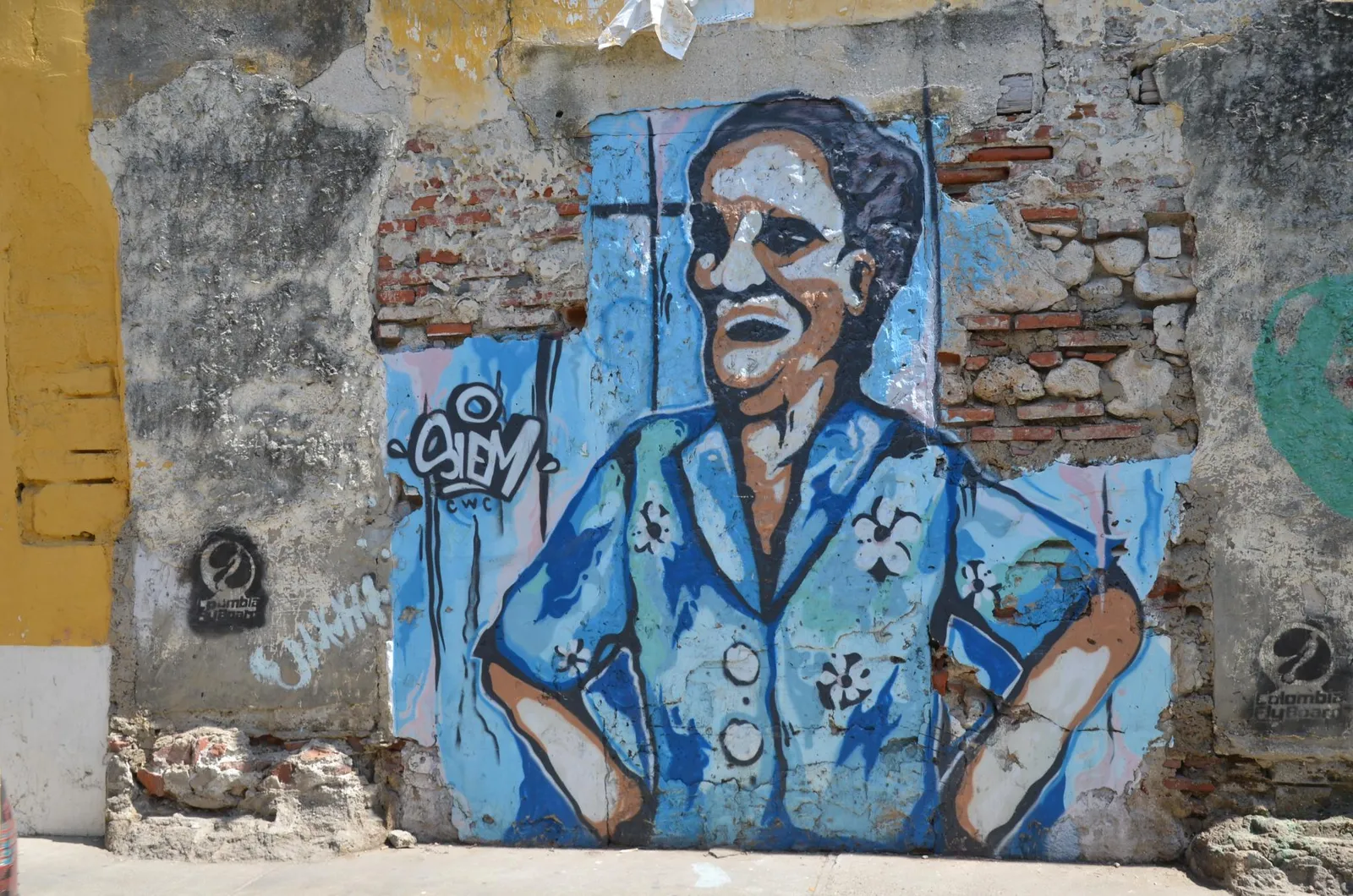 A large, colorful painted mural of a man in a patterned shirt on a weathered stone wall in the Getsemani neighborhood of Cartagena