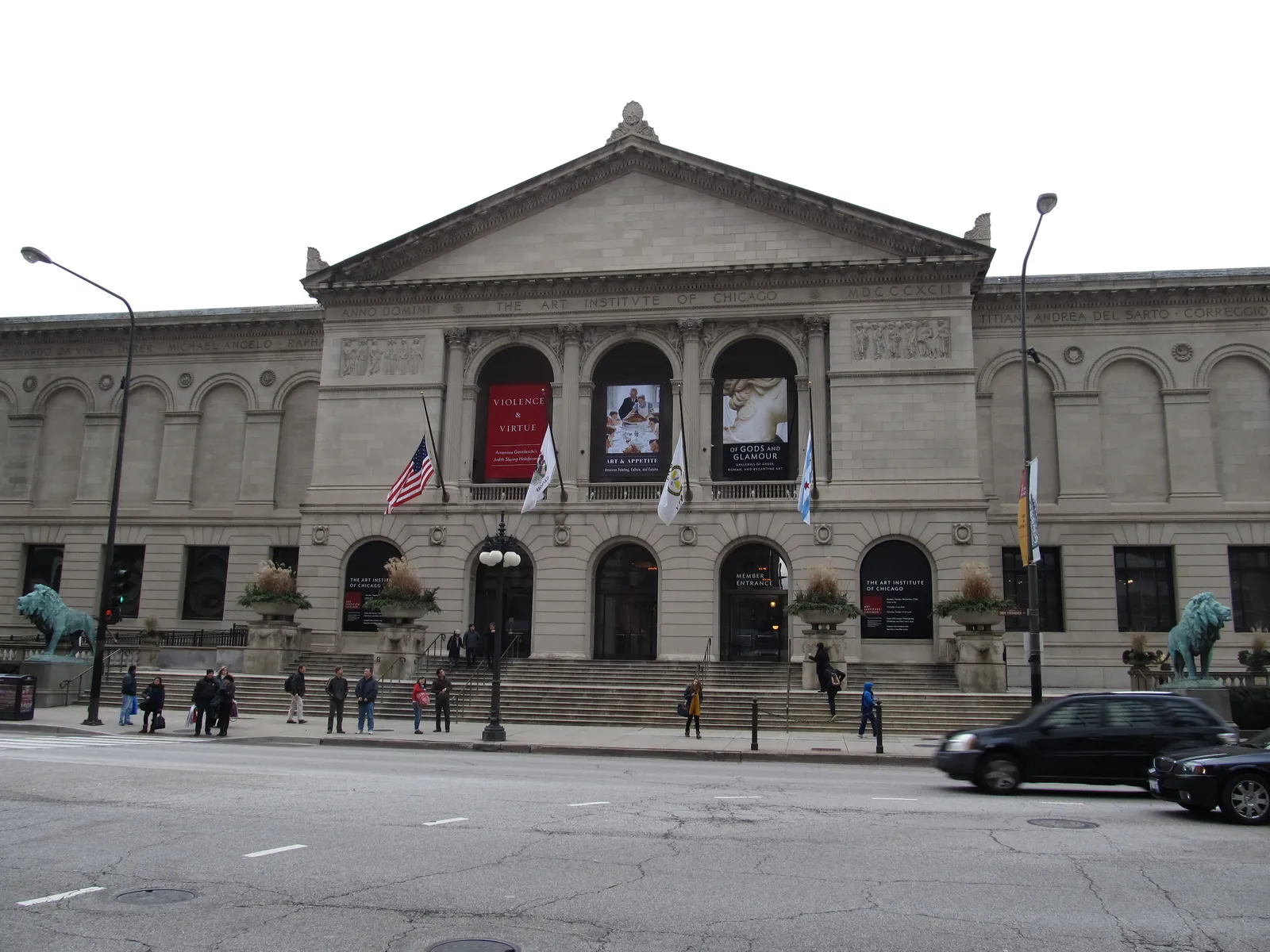 The Art Institute of Chicago's limestone facade on Michigan Avenue, with one of its bronze lion statues on the steps and museum banners hung between the columns