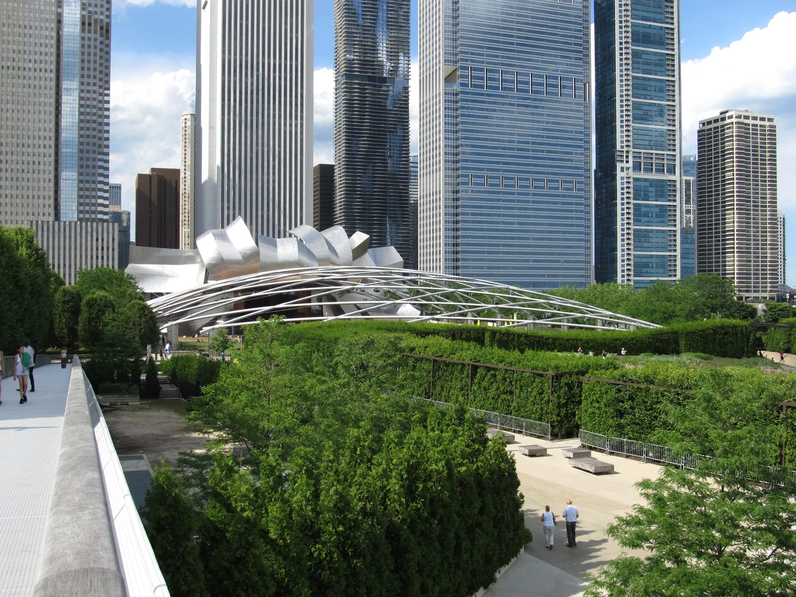 The Jay Pritzker Pavilion's steel-ribboned stage and trellis over the Great Lawn at Millennium Park, with the Loop skyline behind it