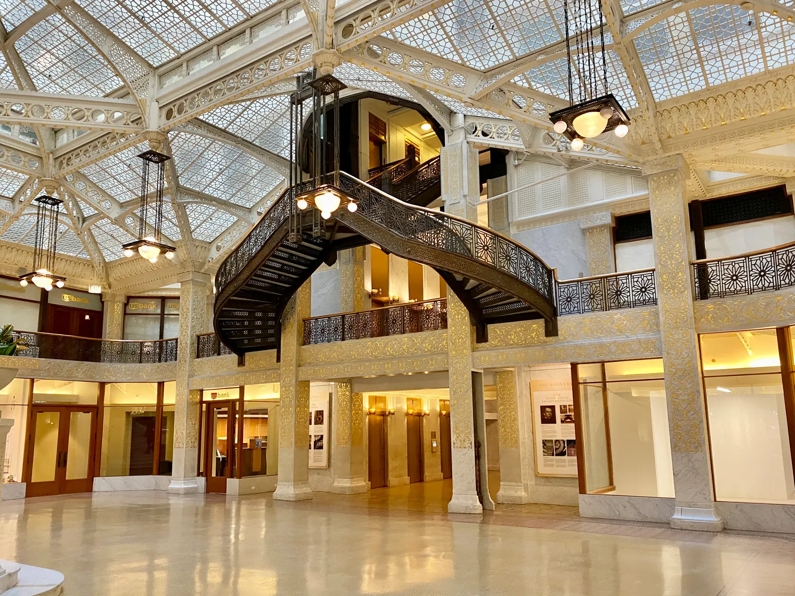 The Rookery Building's glass-roofed light court in Chicago, with Frank Lloyd Wright's gilded ironwork staircase and a two-story ornamented atrium