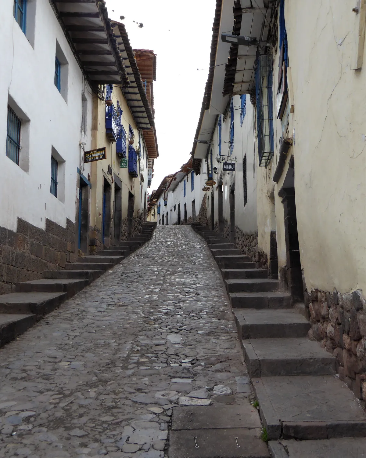The Cuesta de San Blas in Cusco, a narrow cobbled street climbing between whitewashed houses with stepped pavements running up both sides
