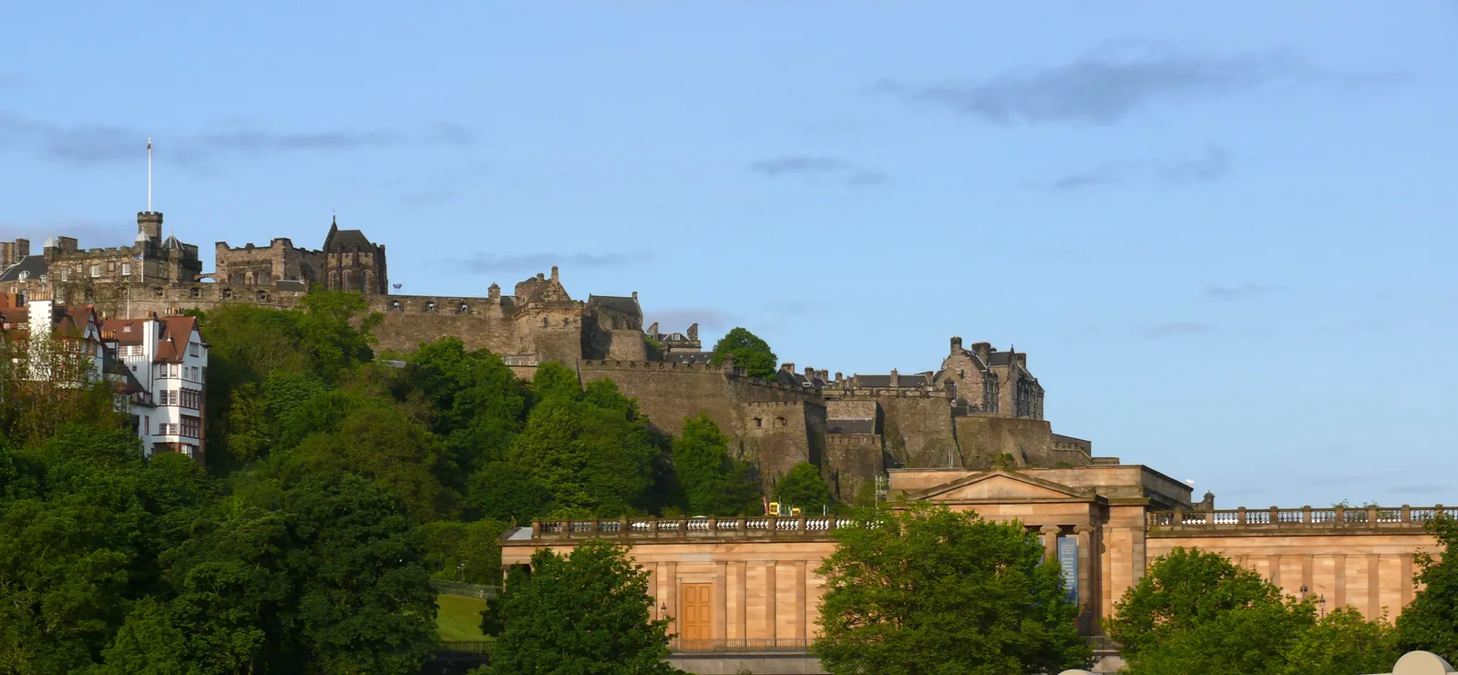 Edinburgh Castle perched on its volcanic rock above the trees and the National Gallery of Scotland