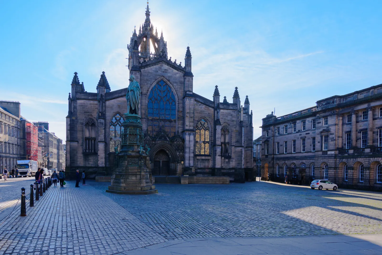 St Giles' Cathedral on Edinburgh's Royal Mile, its open stone crown steeple lit from behind, seen across the cobbles of Parliament Square