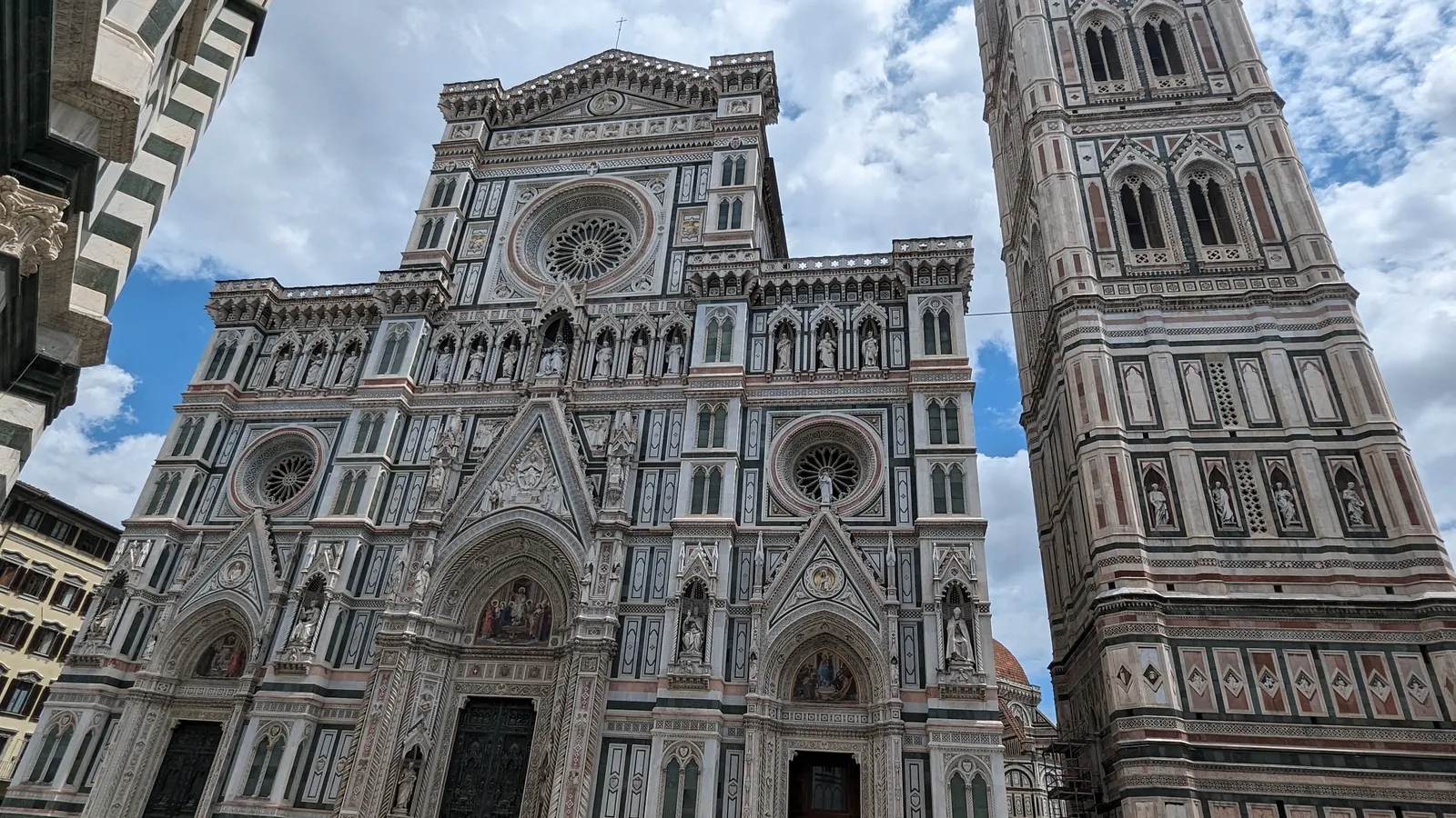 The green, pink, and white marble facade of Florence Cathedral with Giotto's bell tower alongside it