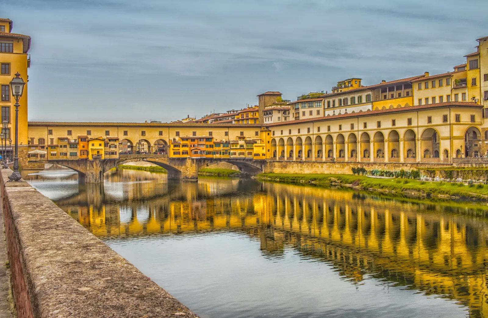 Ponte Vecchio bridge lined with shops reflected in the Arno river in Florence