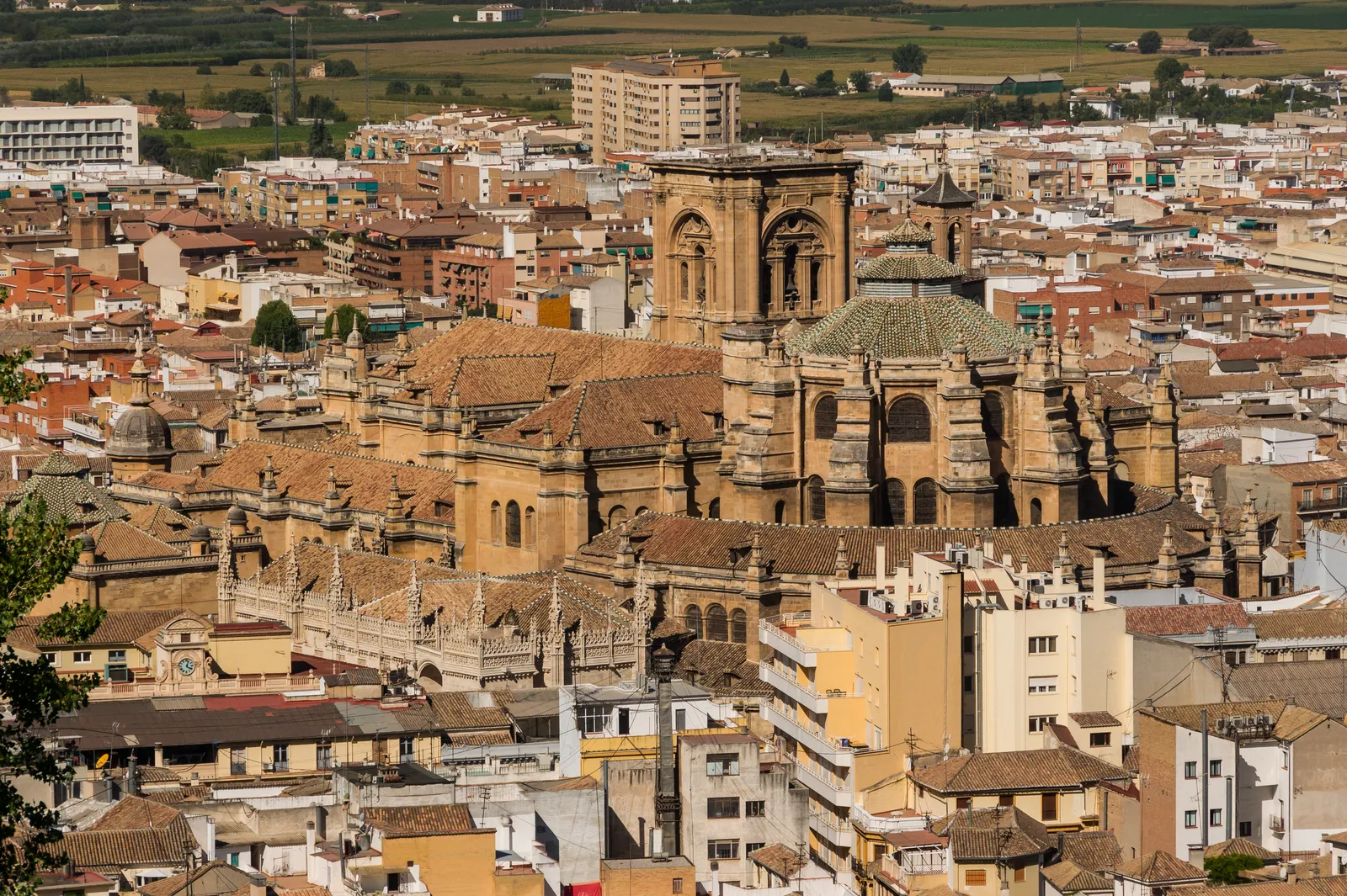 Granada Cathedral and the Royal Chapel seen from above, the cathedral's dome and bell tower rising over the rooftops of the lower town with the chapel's pinnacled Gothic roofline along its side