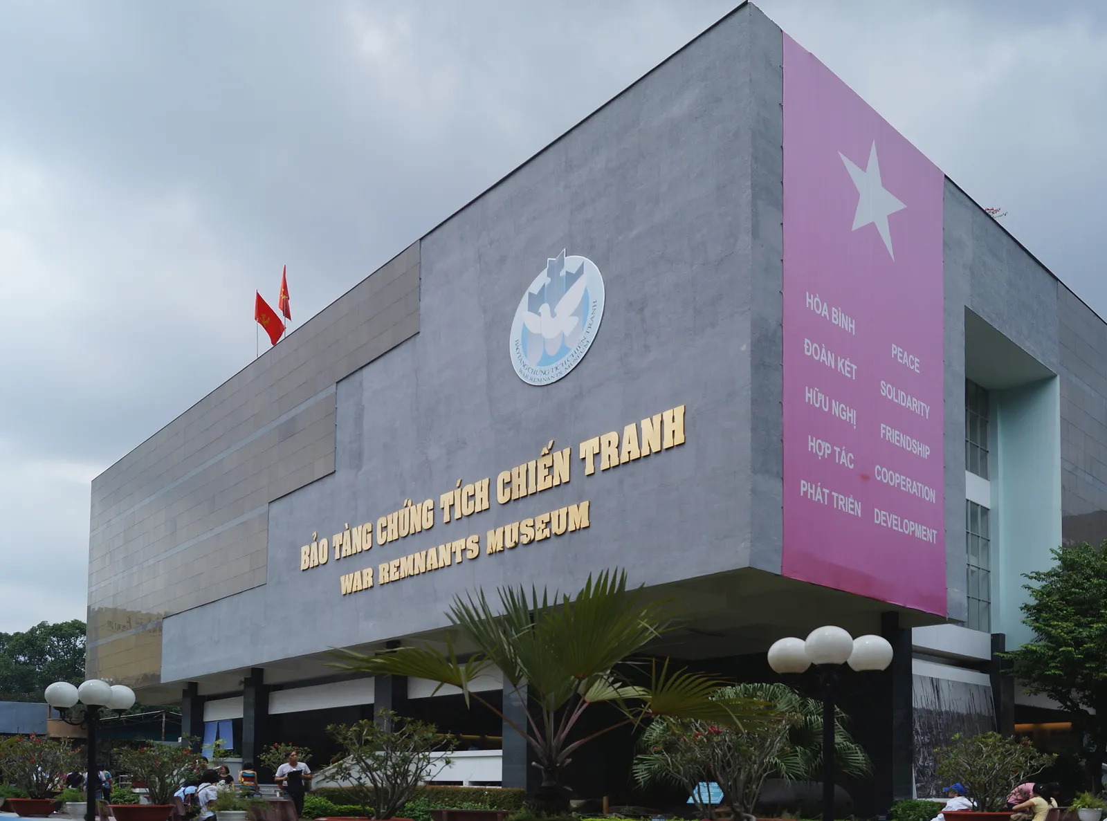 The grey concrete block of the War Remnants Museum in Ho Chi Minh City, its name in Vietnamese and English along the upper wall beside a pink panel listing the words peace, freedom and development