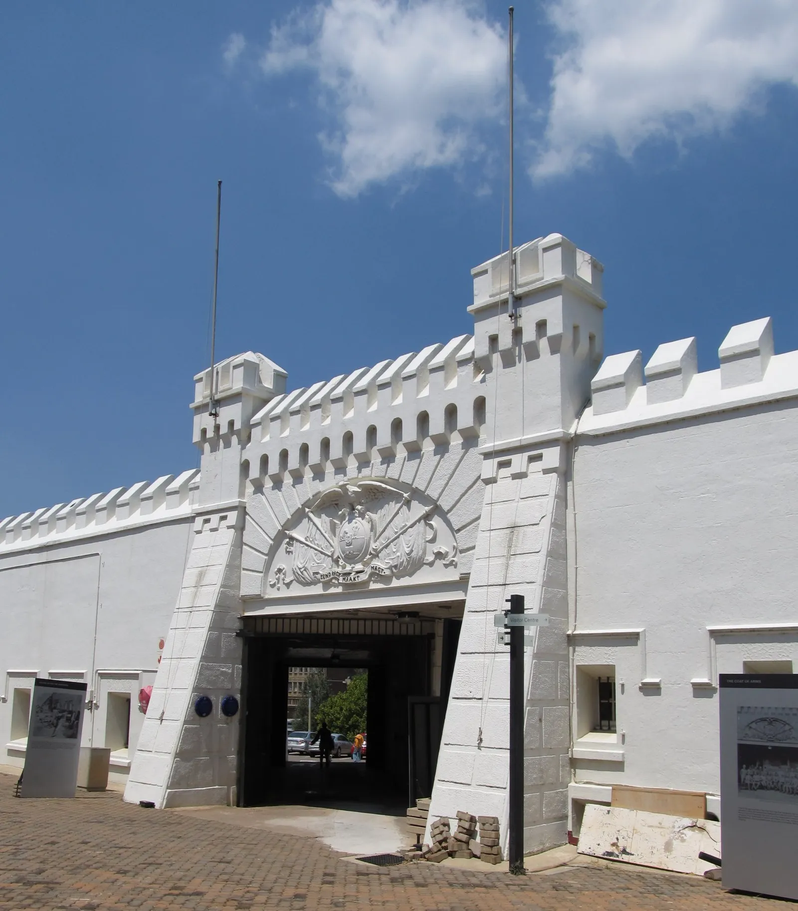 The whitewashed gateway into the Old Fort on Constitution Hill in Johannesburg, crenellated walls either side of a dark arched entrance with a carved coat of arms above it