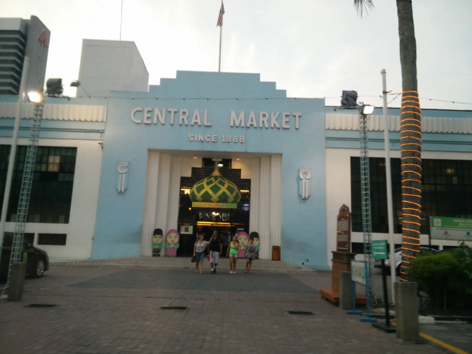 The pale blue art deco front of Central Market in Kuala Lumpur with the words Central Market Since 1888 across it, shoppers walking out through the central archway