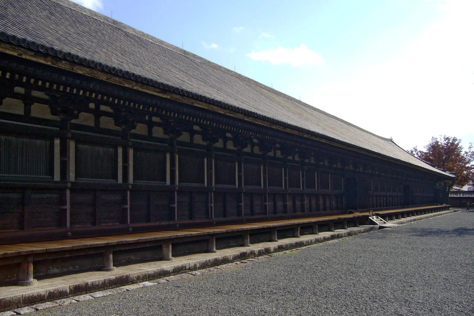 The main hall at Sanjusangendo in Kyoto seen down its full length, a single low wooden building with a tiled roof and rank after rank of identical bays running away into the distance