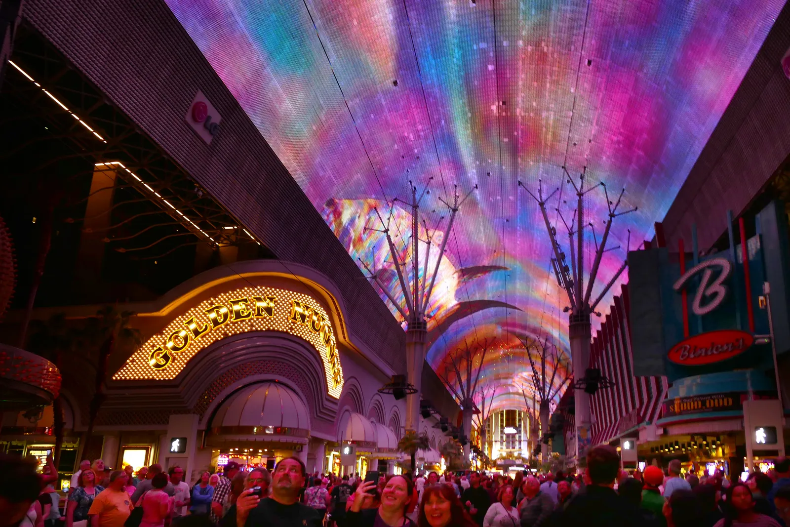 The lit Viva Vision canopy arching over Fremont Street in downtown Las Vegas, with the Golden Nugget sign on the left and a crowd filling the mall below