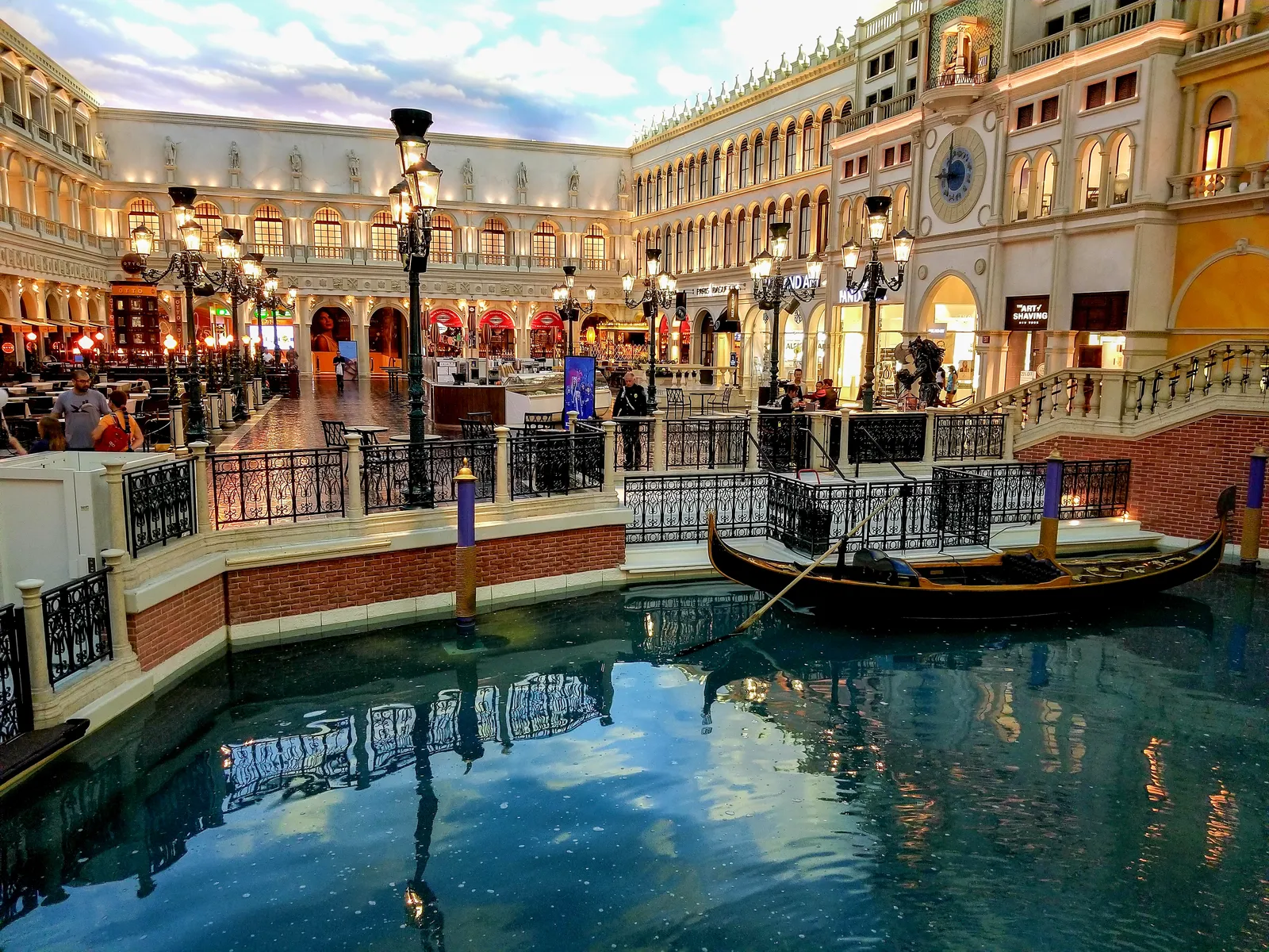 The indoor Grand Canal inside the Venetian in Las Vegas, a gondola on green water between brick walkways and arcaded shopfronts under a painted sky ceiling
