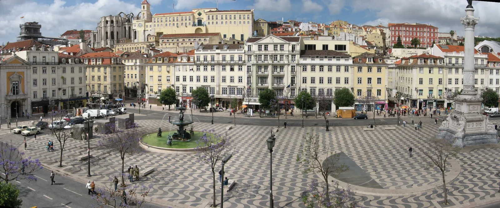 Rossio square in Lisbon, its black and white wave-patterned pavement running the length of the square past a bronze fountain and the column of Dom Pedro IV