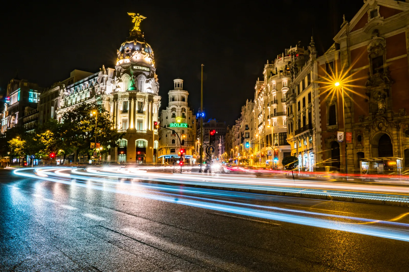 The domed corner of the Metropolis Building on Gran Vía at night, with light trails from traffic below