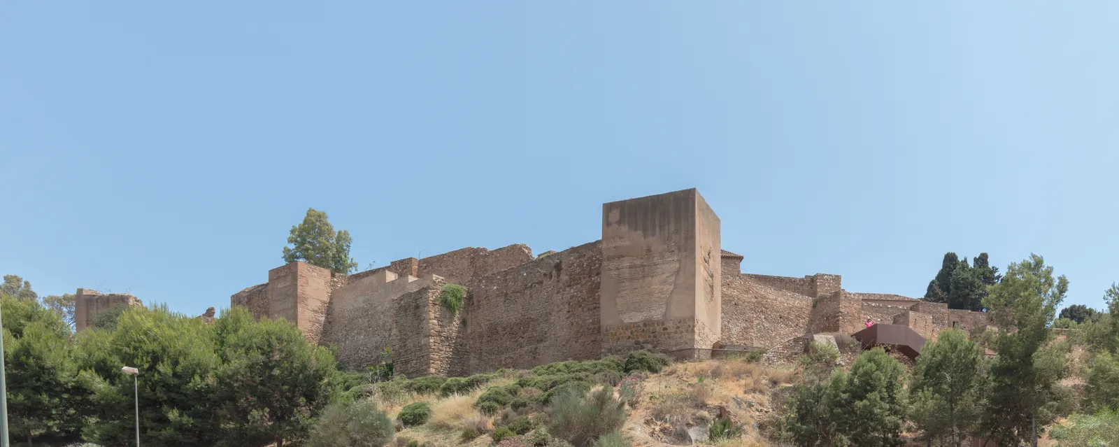 The Alcazaba of Málaga's stone Moorish fortress walls and towers rising above trees on the hillside