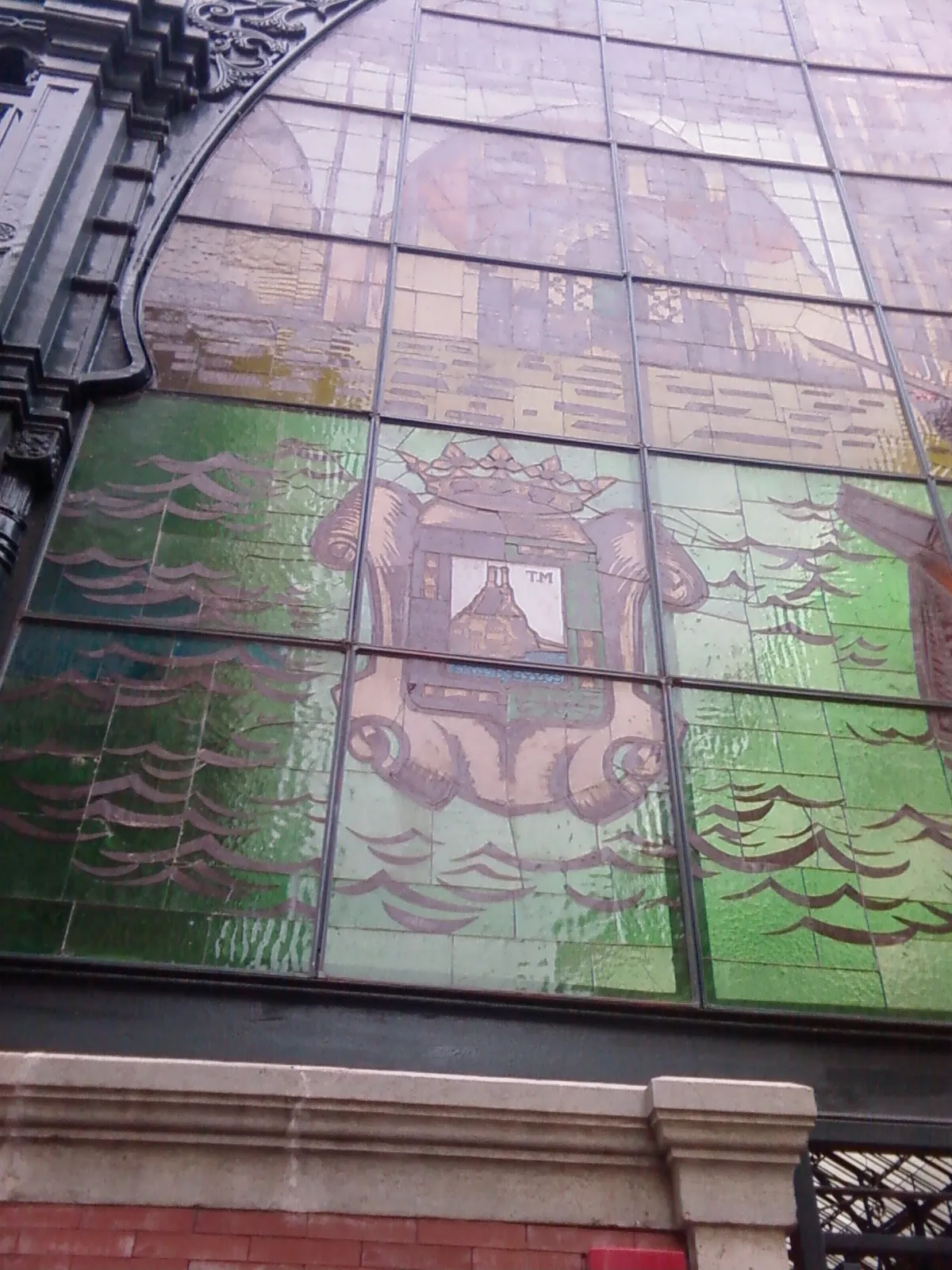 A close-up of the 1973 stained-glass window over Atarazanas Market in Málaga, showing the city's coat of arms in green and gold glass