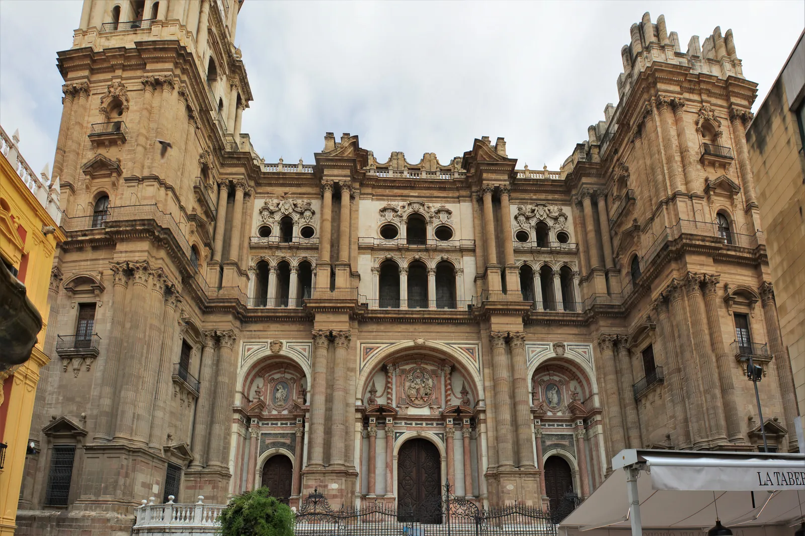 Málaga Cathedral's ornate stone facade, with its single completed bell tower beside the unfinished second tower