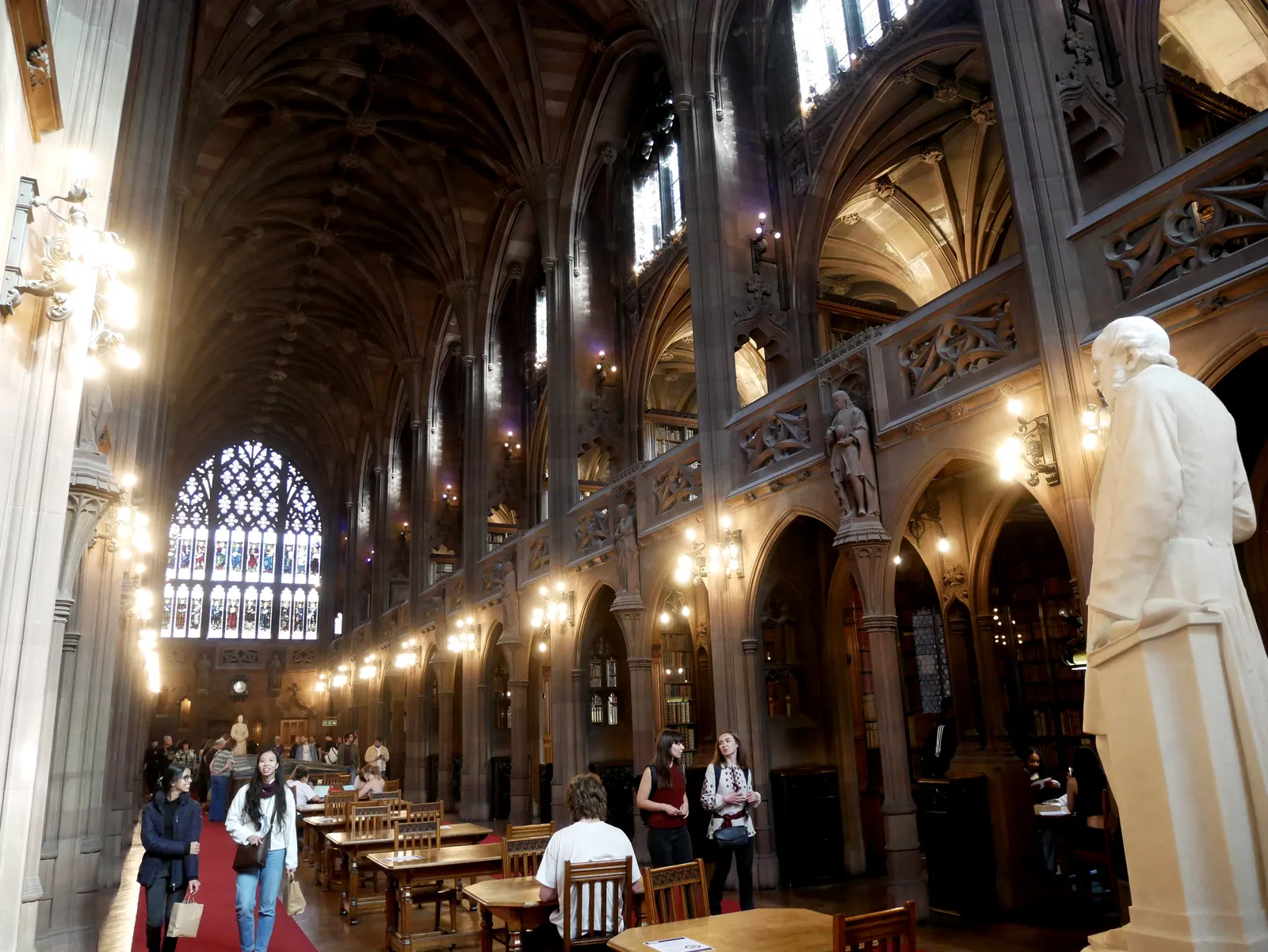 The vaulted Gothic reading room of John Rylands Library in Manchester, lined with arches, statues and reading desks