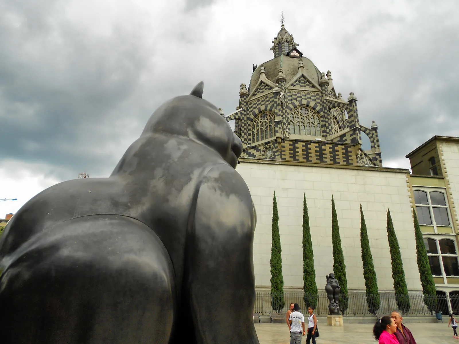 The black-and-white Gothic Revival towers of the Palacio de la Cultura Rafael Uribe Uribe in Medellín, seen past one of Fernando Botero's bronze sculptures in Plaza Botero