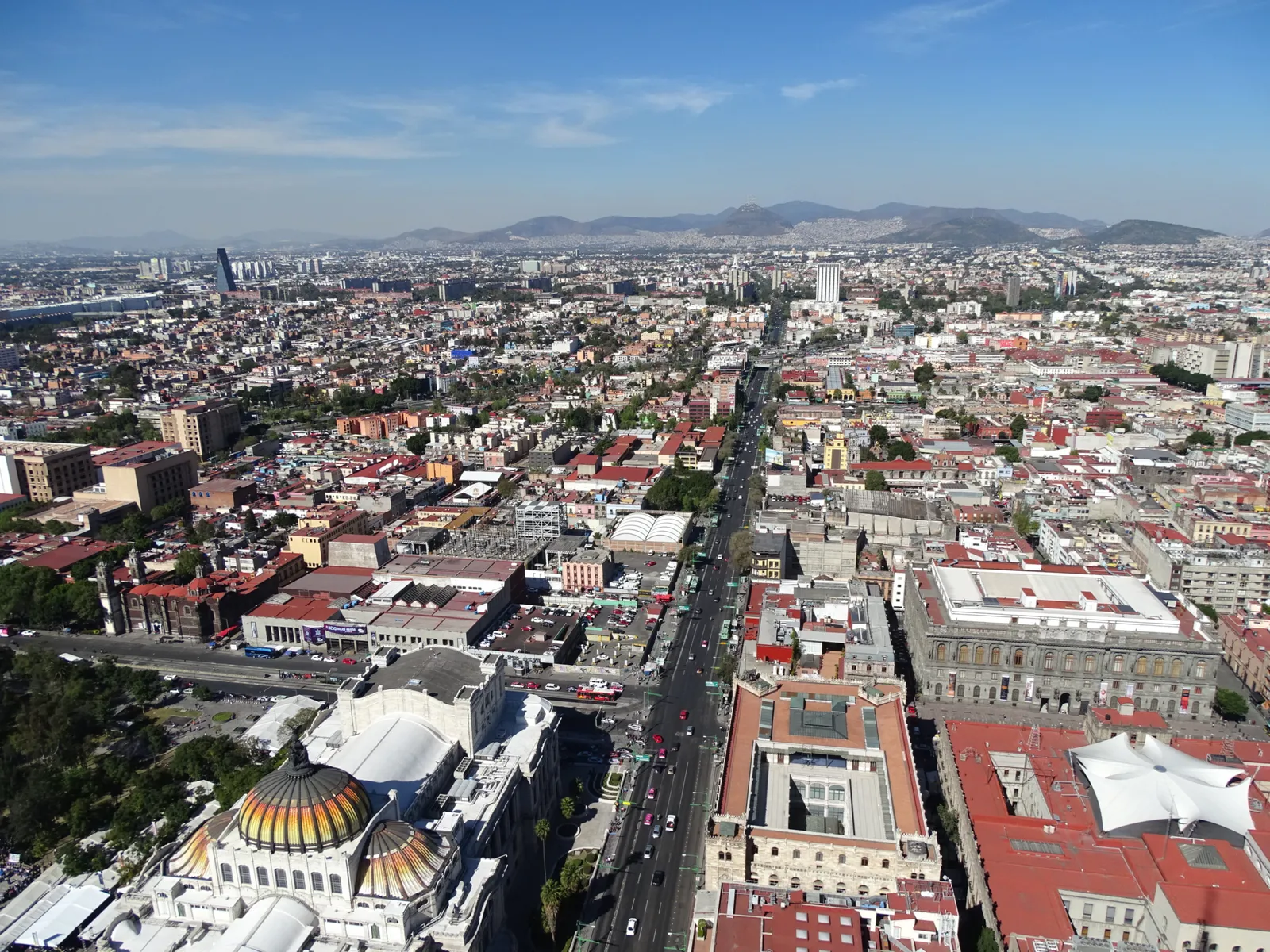 Mexico City's historic centre seen from the top of Torre Latinoamericana, with the coloured dome of the Palacio de Bellas Artes in the lower left and the street grid running out to mountains on the horizon
