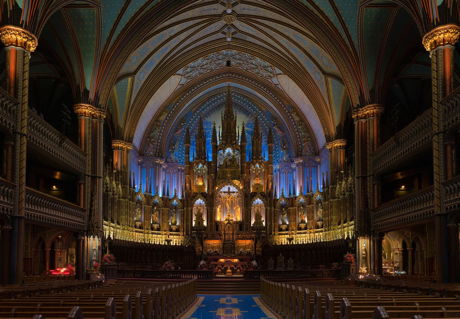 The interior of Notre-Dame Basilica in Montreal looking down the nave to the altarpiece, the ribbed vaults above painted deep blue and scattered with gold stars