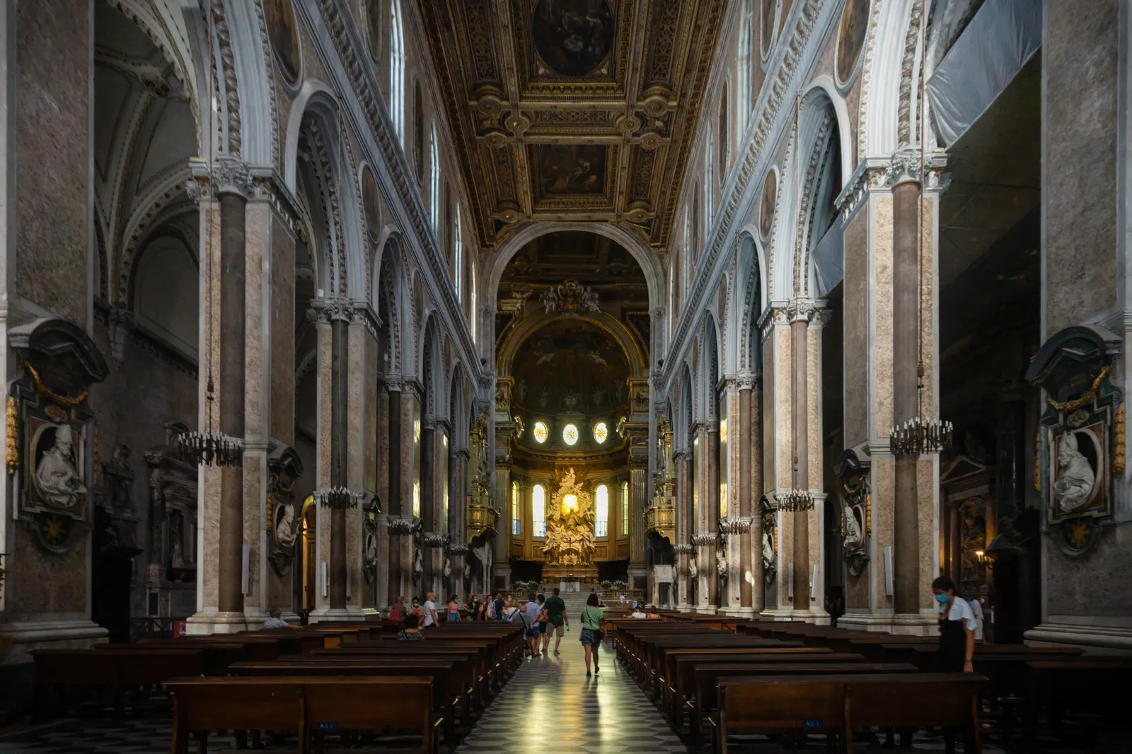 The central nave of Naples Cathedral, lined with marble columns under a gilded coffered ceiling