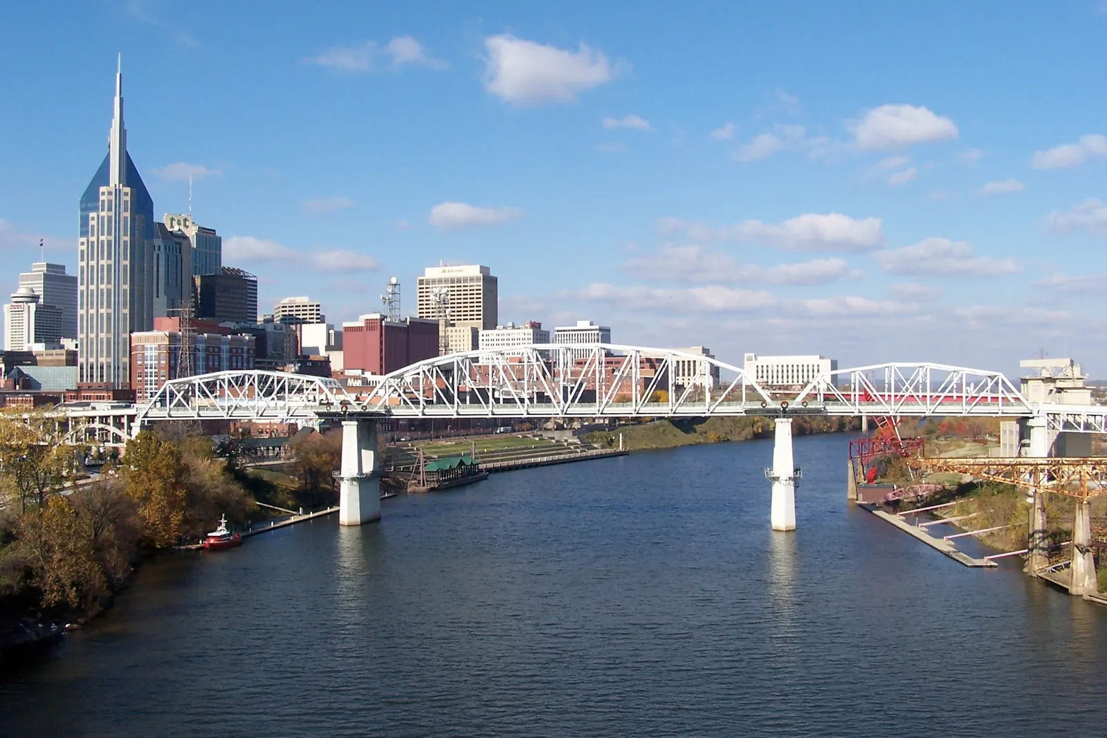 The white steel truss span of the John Seigenthaler Pedestrian Bridge crossing the Cumberland River in Nashville, with the downtown skyline on the left bank