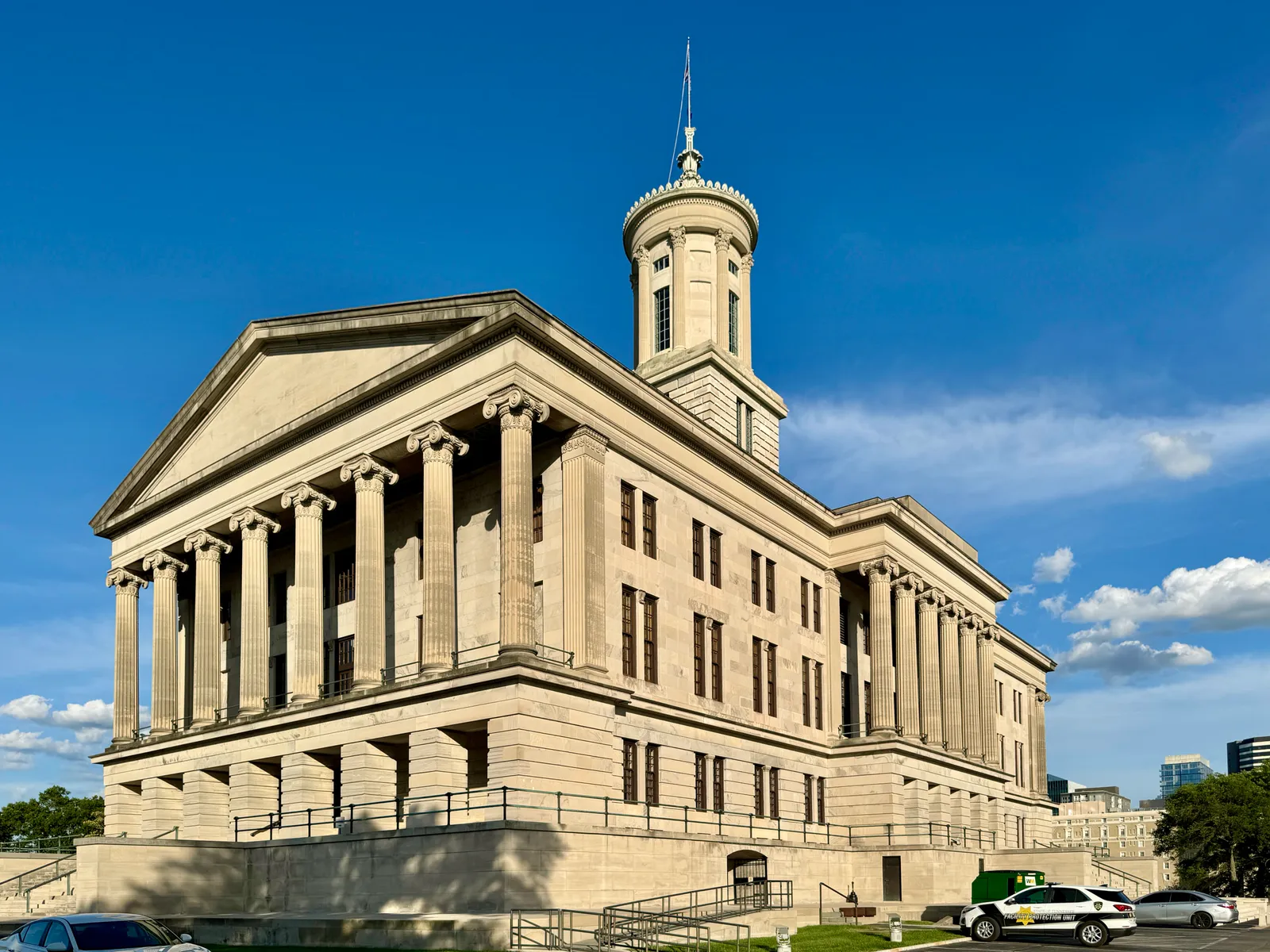 The Tennessee State Capitol in Nashville, a limestone Greek Revival building with Ionic porticoes and a tall octagonal lantern tower, standing above a retaining wall on Capitol Hill