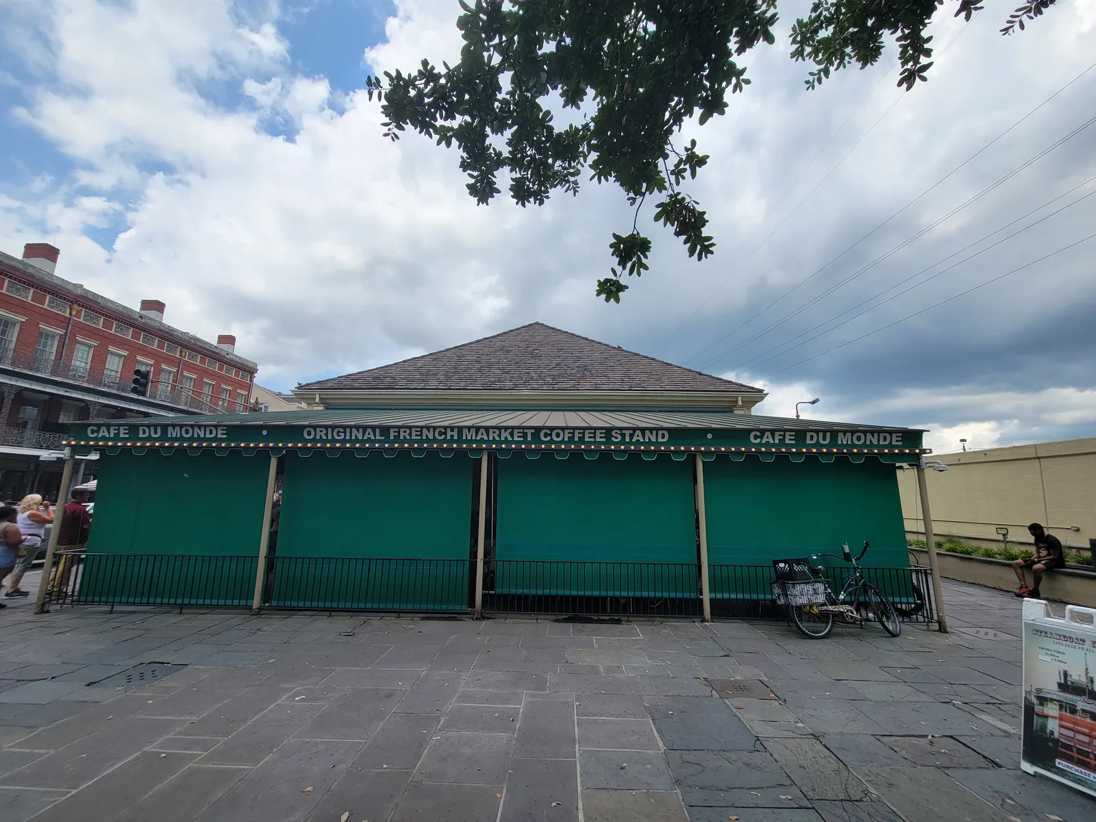 The green and white awning of the Cafe du Monde coffee stand on Decatur Street in New Orleans, its lettering reading Original French Market Coffee Stand along the front