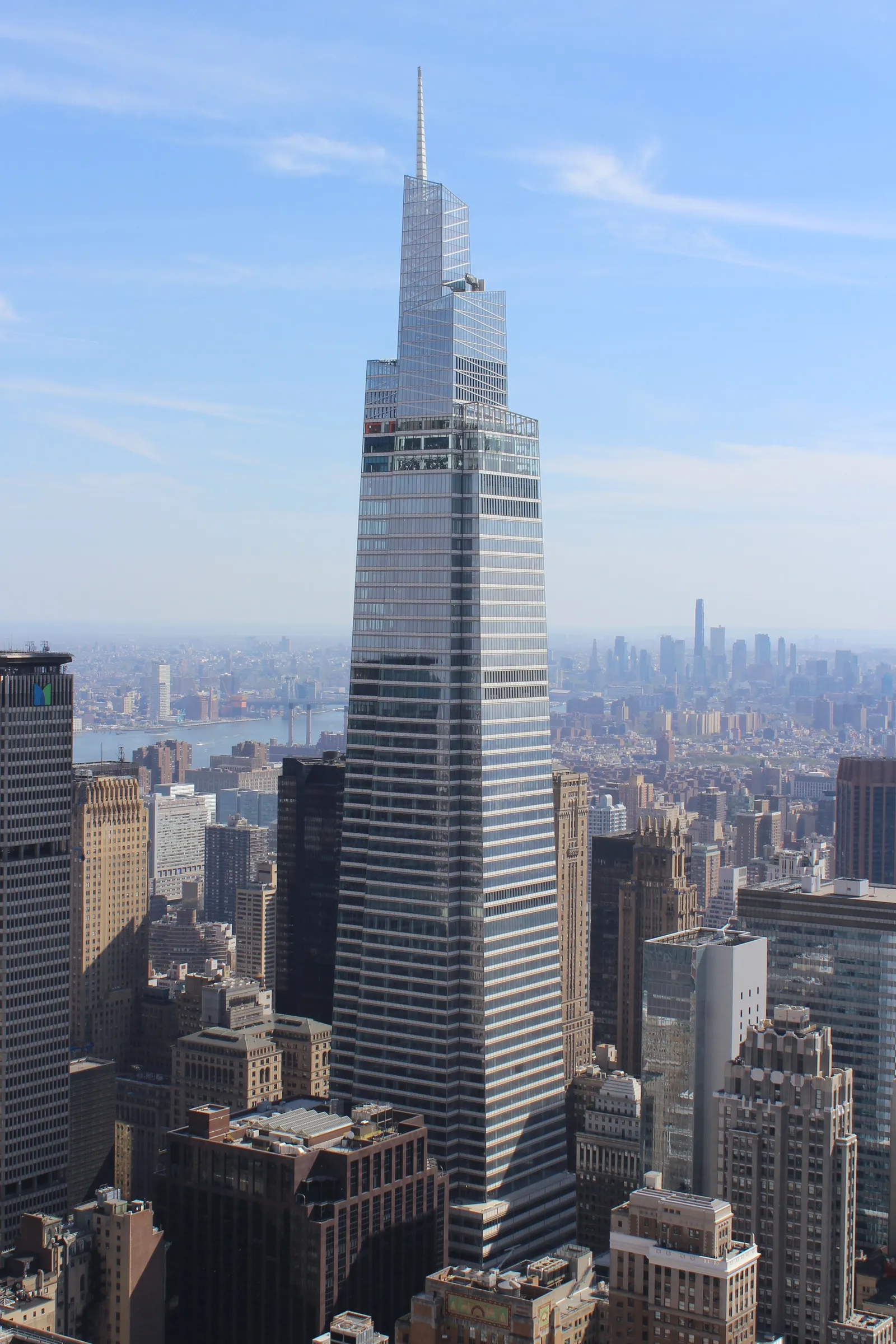 The One Vanderbilt tower rising above the surrounding Midtown Manhattan blocks, its glass sides stepping inward toward the angled top floors where the observation deck sits