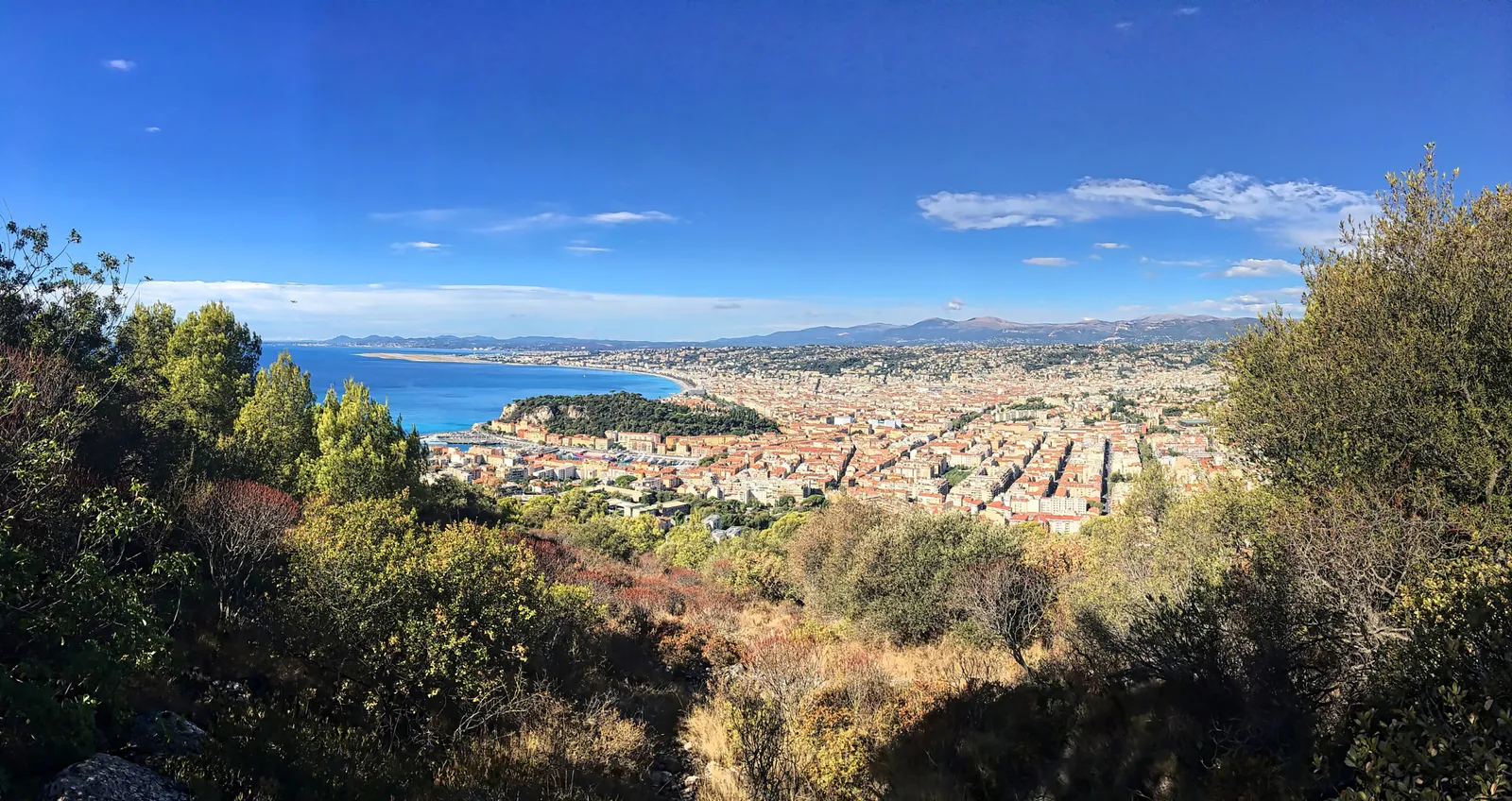 Panoramic view from Castle Hill over Nice's old town rooftops, the harbor, and the Baie des Anges