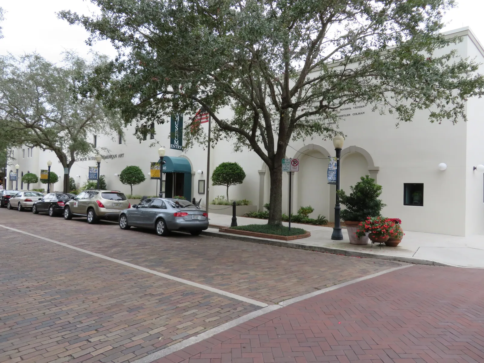 The low white front of the Morse Museum of American Art on Winter Park's brick-paved Park Avenue, its green awning shaded by oak trees