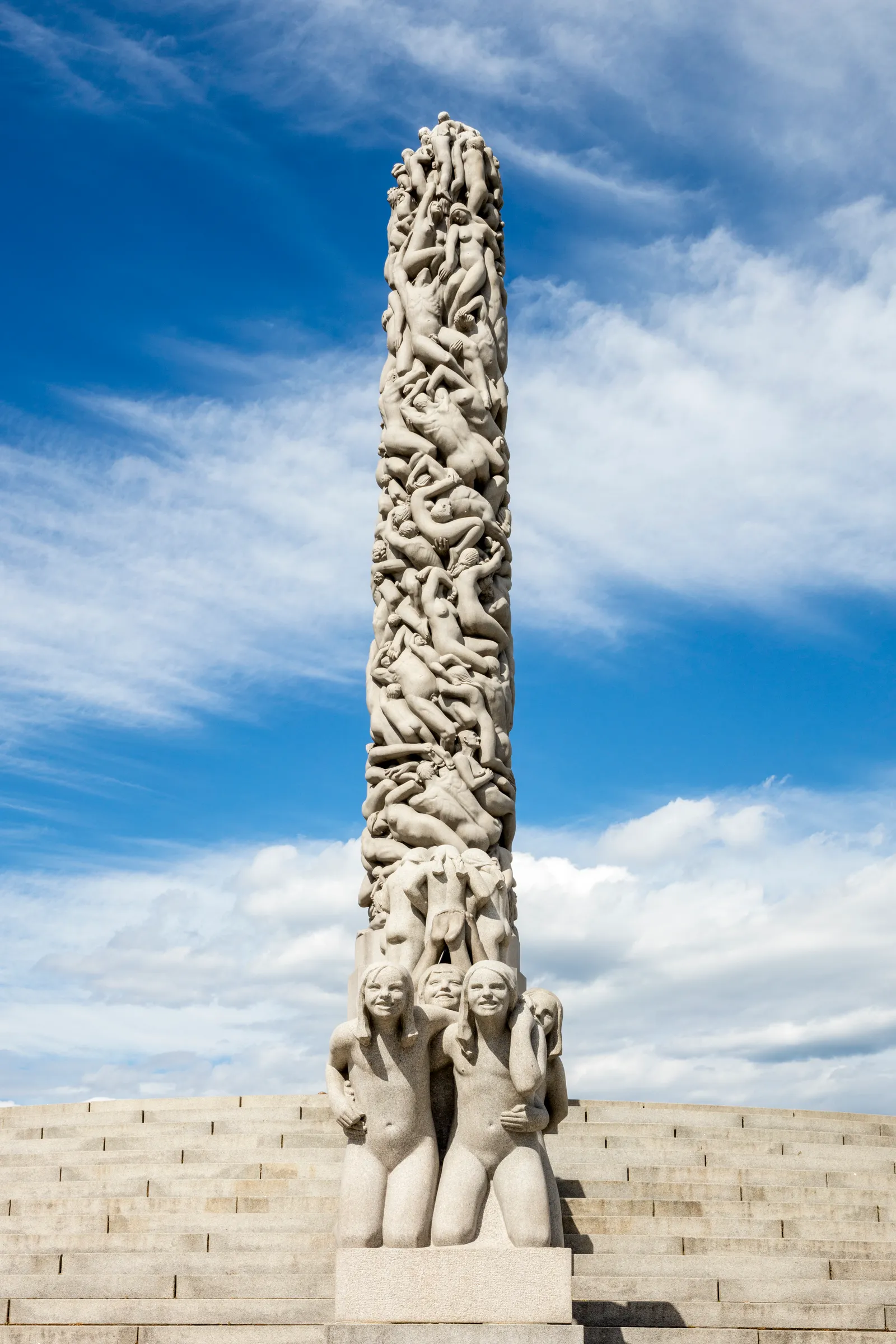 The Monolith in Frogner Park, Oslo, a single granite column carved with intertwined human figures rising above a group of kneeling stone figures on the steps at its base