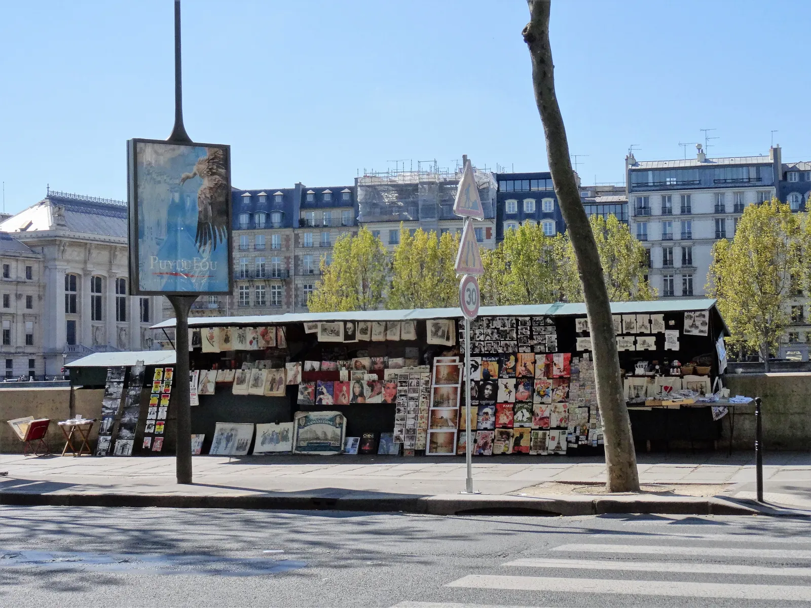 Green bouquiniste bookstalls lining the Seine embankment near Quai de la Mégisserie, with Parisian apartment buildings behind