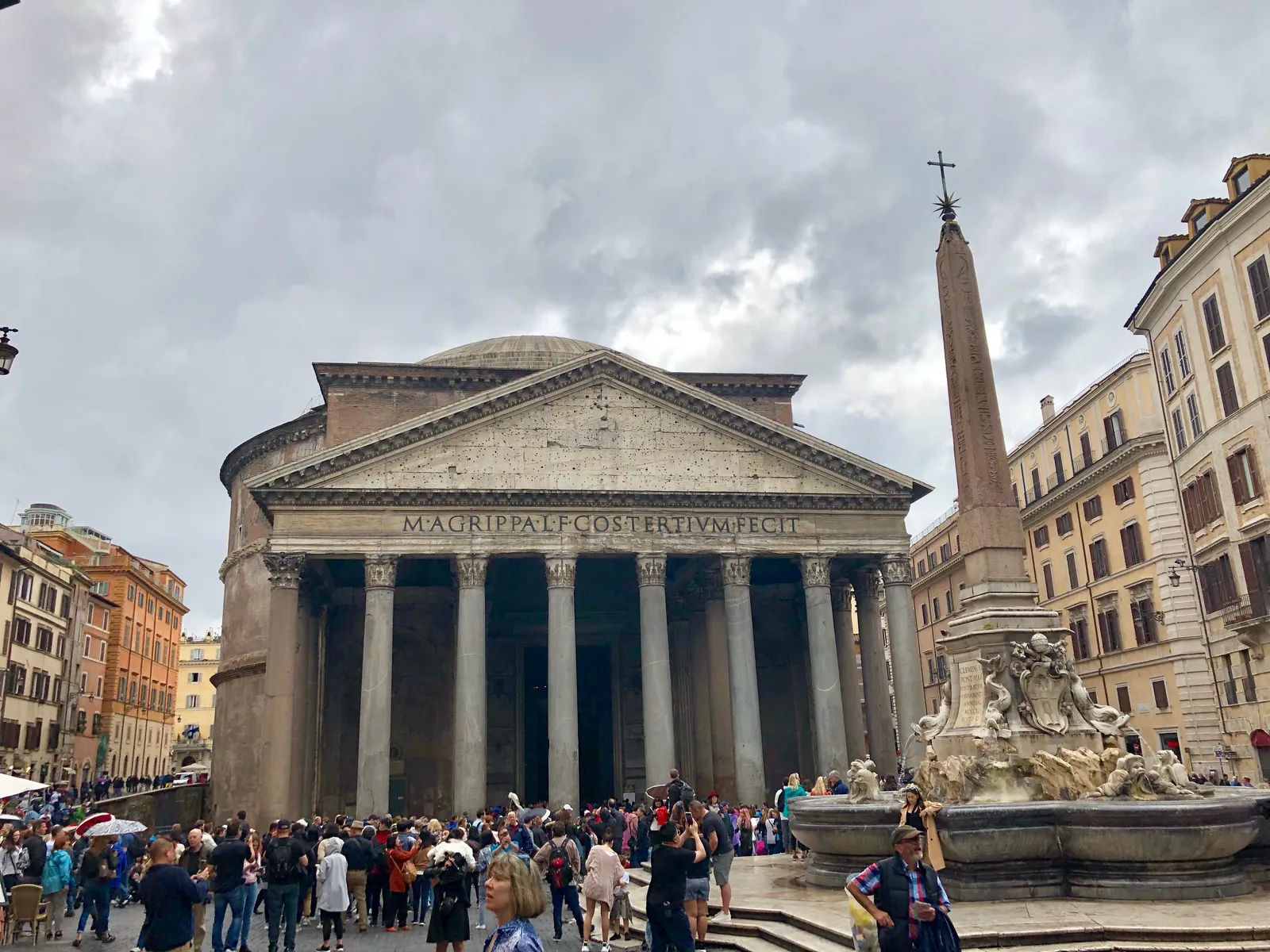 The Pantheon in Rome seen from Piazza della Rotonda, its granite portico columns and carved inscription facing the square, with the Egyptian obelisk and fountain standing in front of it
