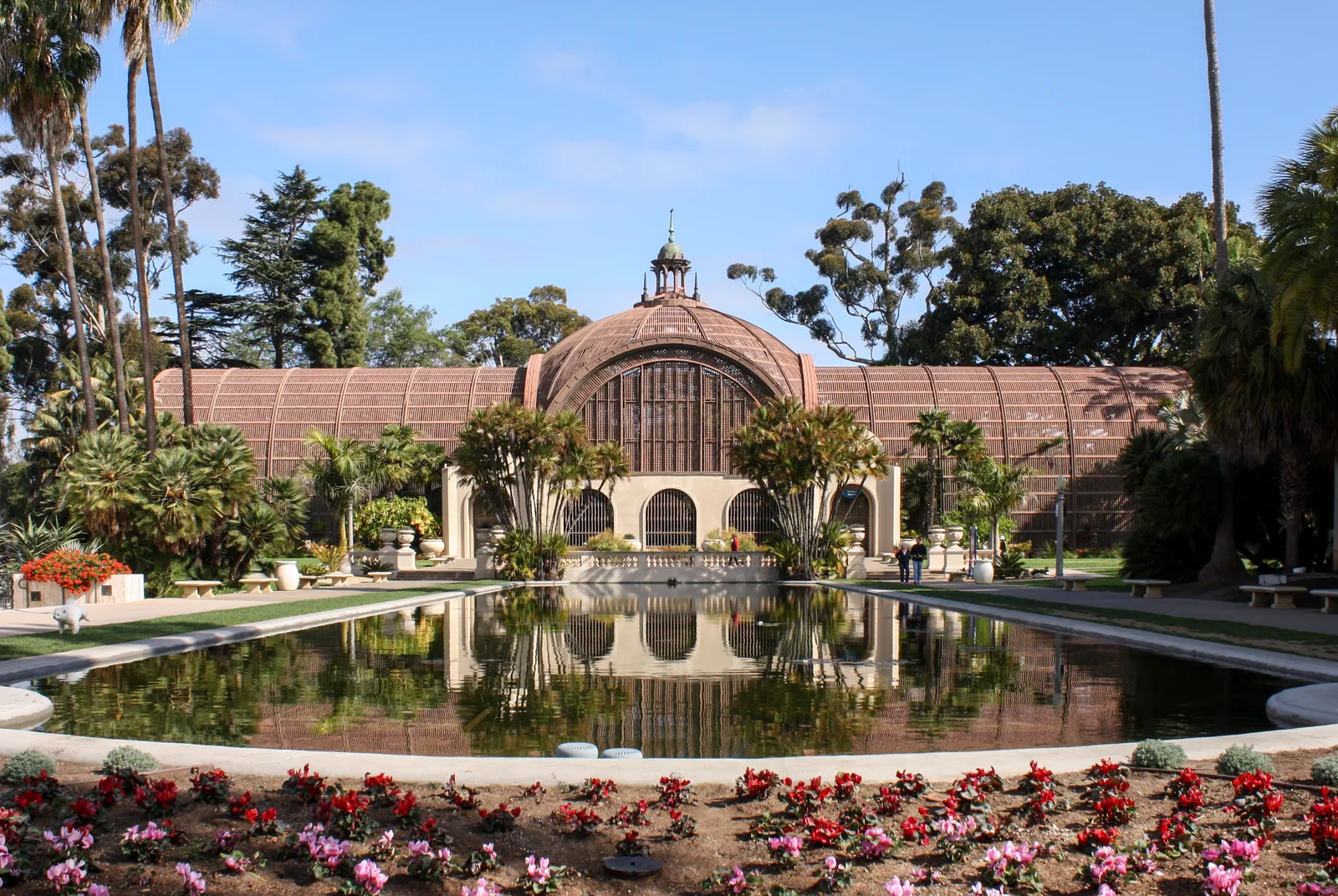 The domed wooden lath front of the Botanical Building in Balboa Park, San Diego, mirrored in the long lily pond with flower beds in the foreground