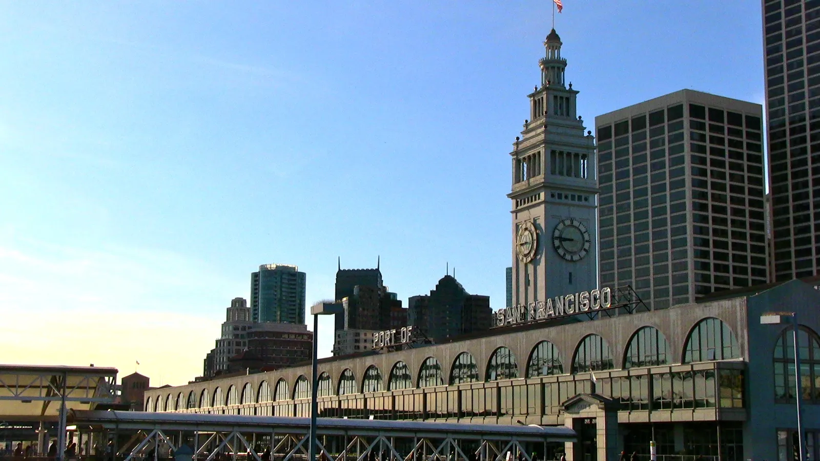 The San Francisco Ferry Building on the Embarcadero, a long arcaded hall with PORT OF SAN FRANCISCO across its front and a tall stone clock tower rising above the middle of it