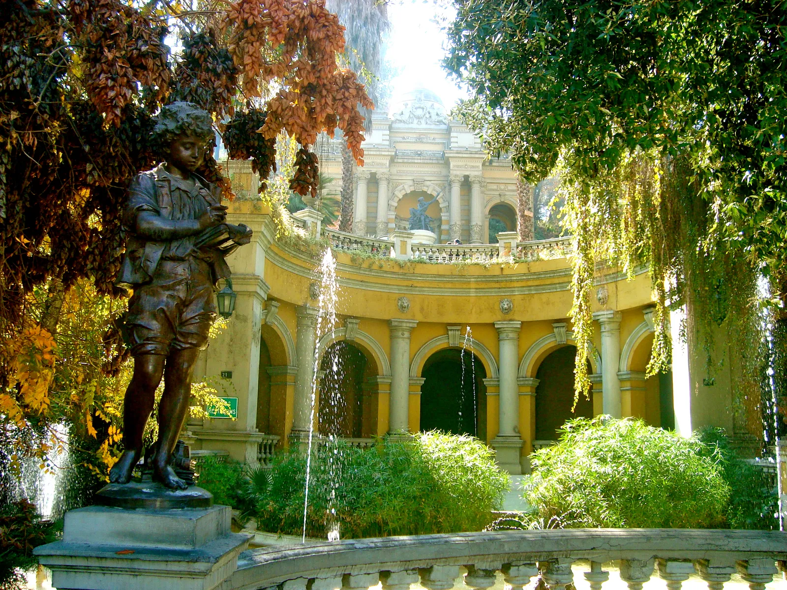 The curved yellow stone arcade and fountains of the Neptune Terrace on Cerro Santa Lucía in Santiago, framed by autumn foliage and creepers
