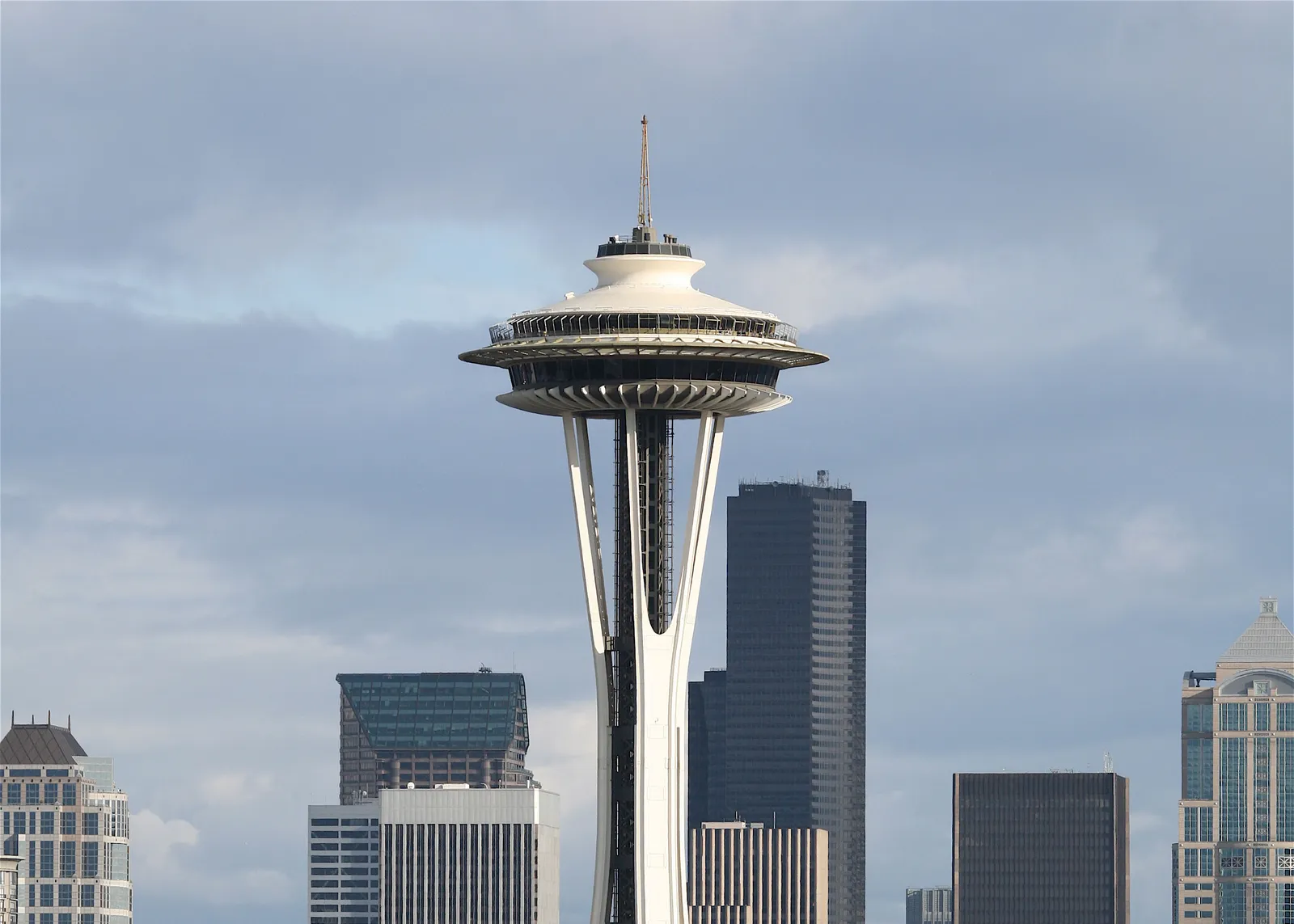 The Space Needle's flying-saucer observation deck and tapered legs rising in front of the downtown Seattle office towers