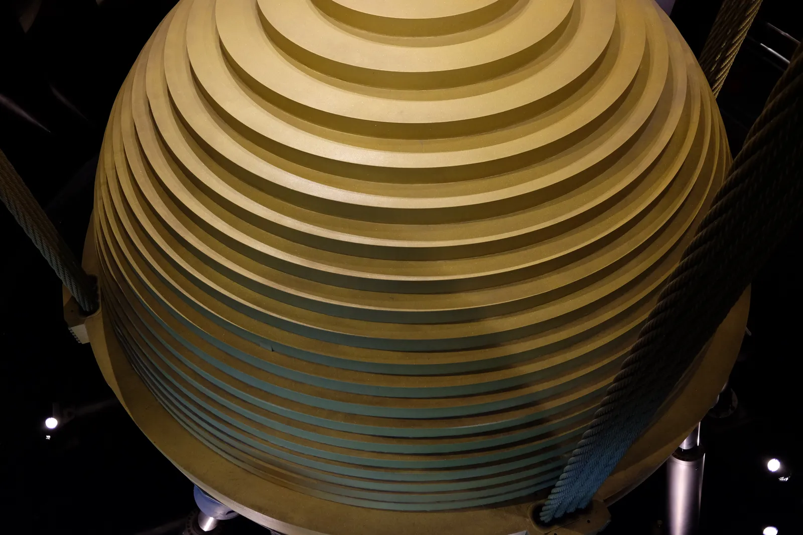 The gold-coloured tuned mass damper inside Taipei 101, a ball of stacked steel plates hanging on thick steel cables in a dark shaft
